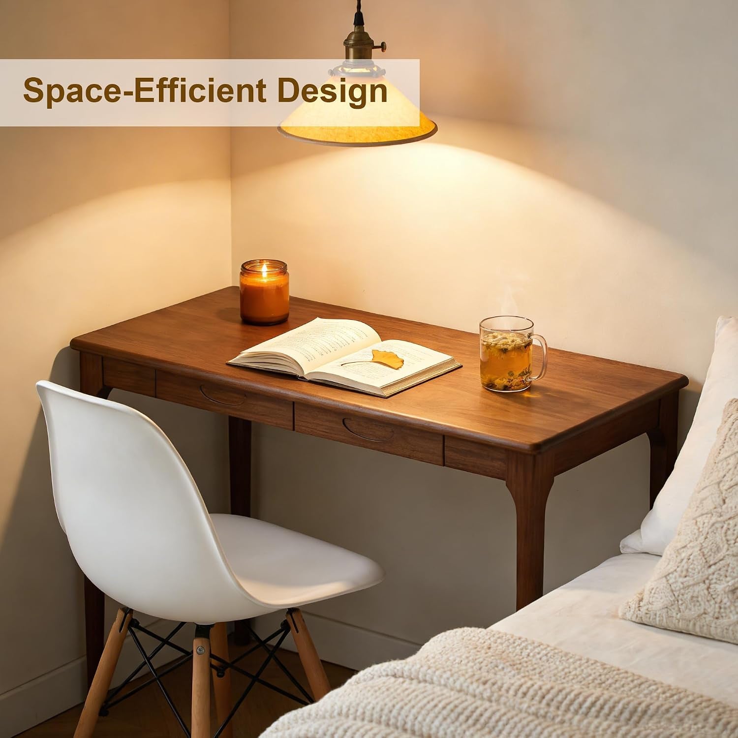 Walnut desk tucked into a cozy corner with a white chair, lit pendant, candle, open book and a mug.