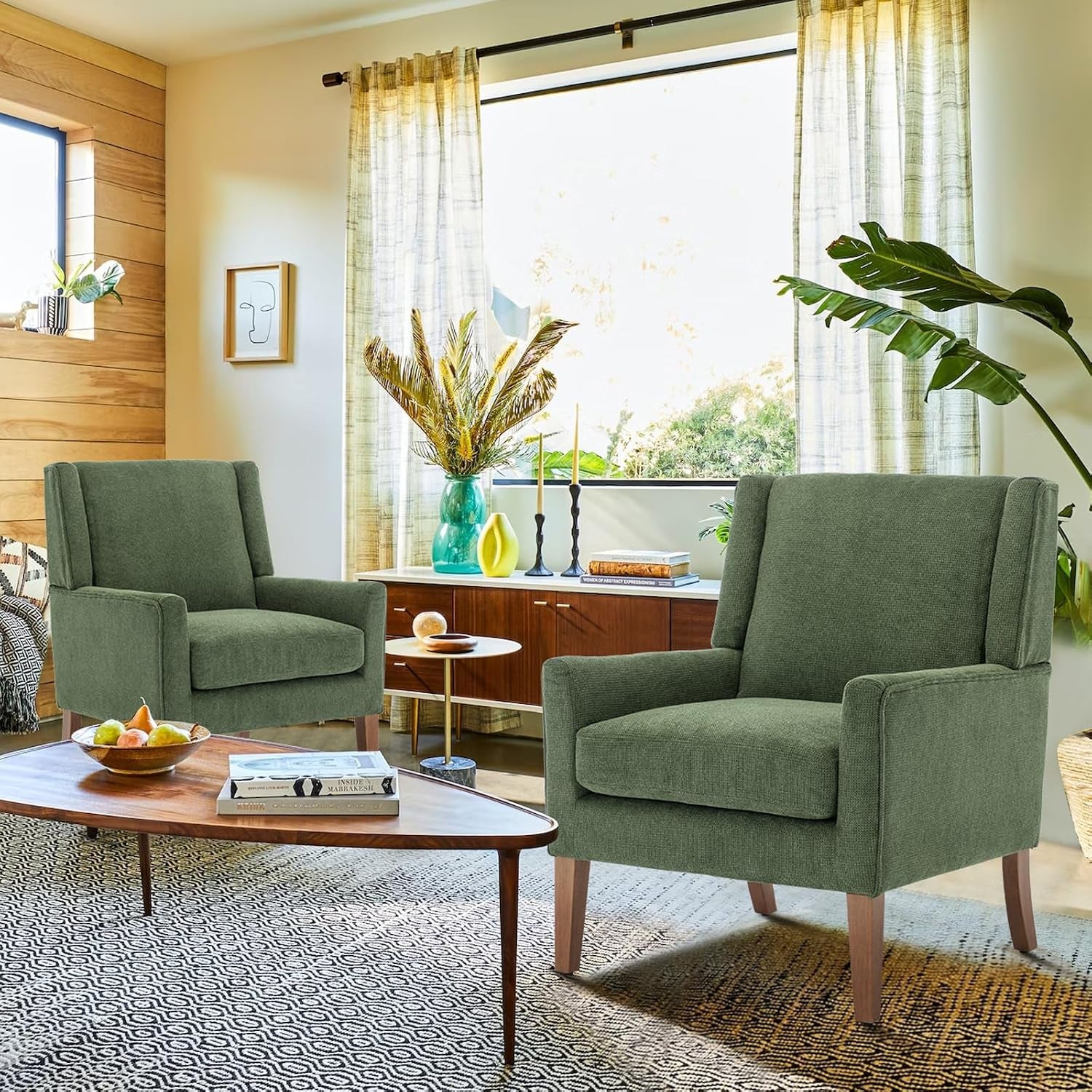 Pair of green wingback accent chairs arranged in a bright living room with mid-century style decor