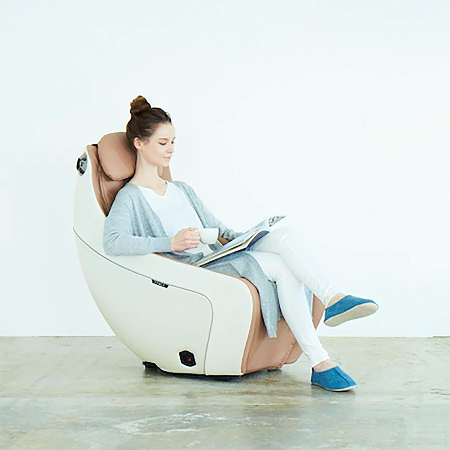 Woman seated reading in beige massage chair in a bright minimalist room, side view