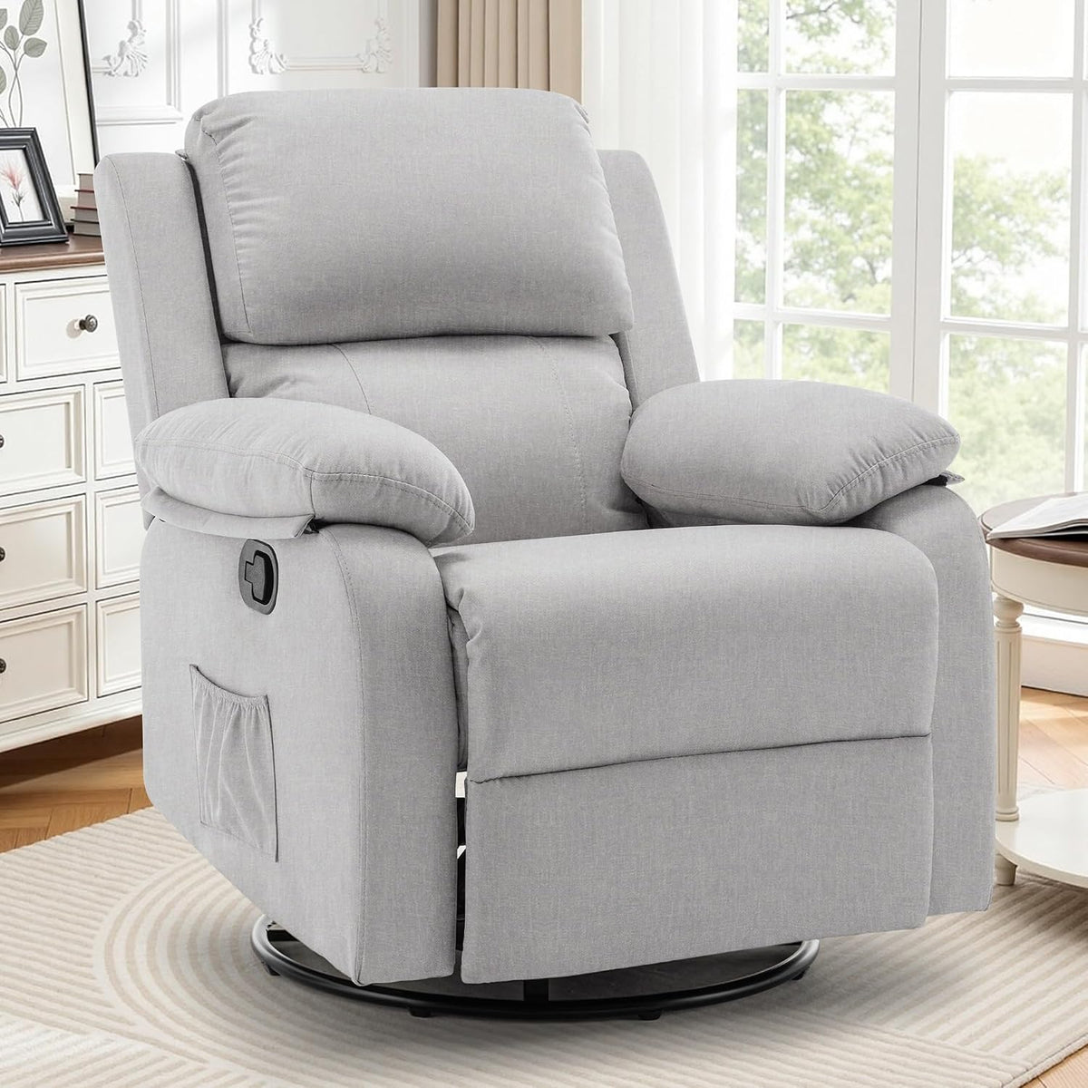 Light gray fabric swivel recliner placed on a patterned rug in front of large windows.