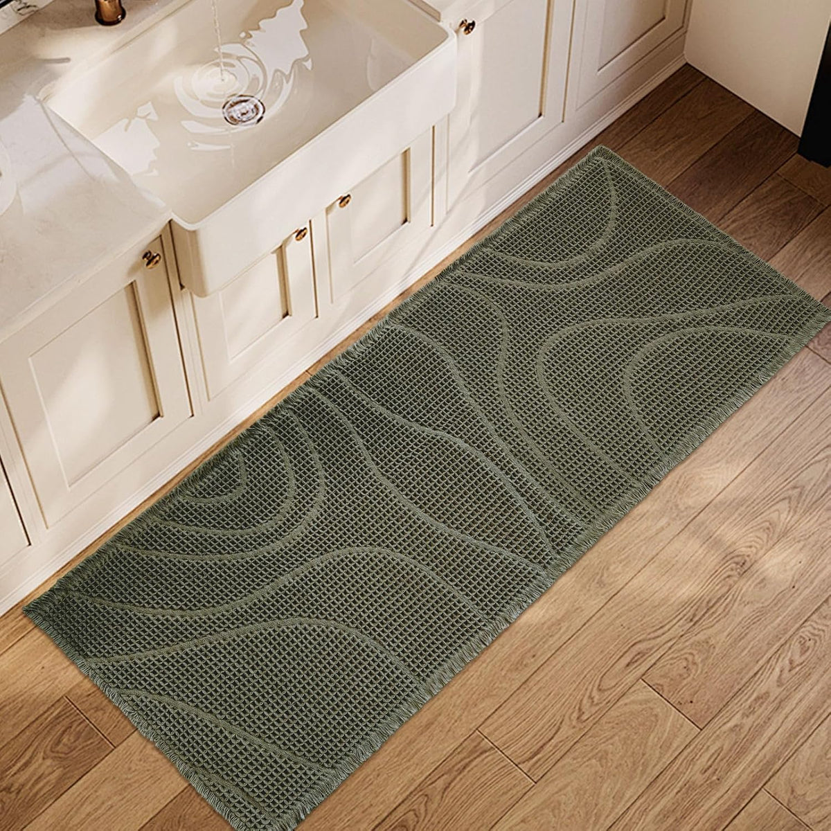Olive-green rectangular mat with wavy waffle texture placed along a bathroom cabinet on wood floor.