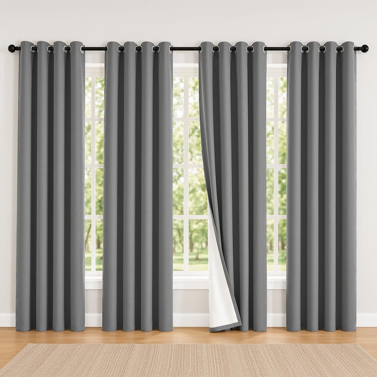 Dark grey curtains hung across a wide window with a single panel pulled back to show white lining