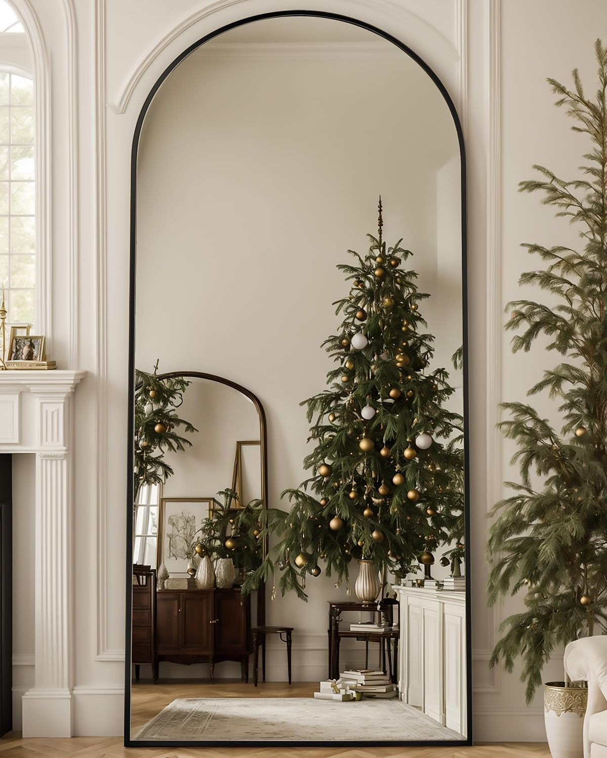 Large arched mirror with a black frame reflecting a room and a decorated Christmas tree.
