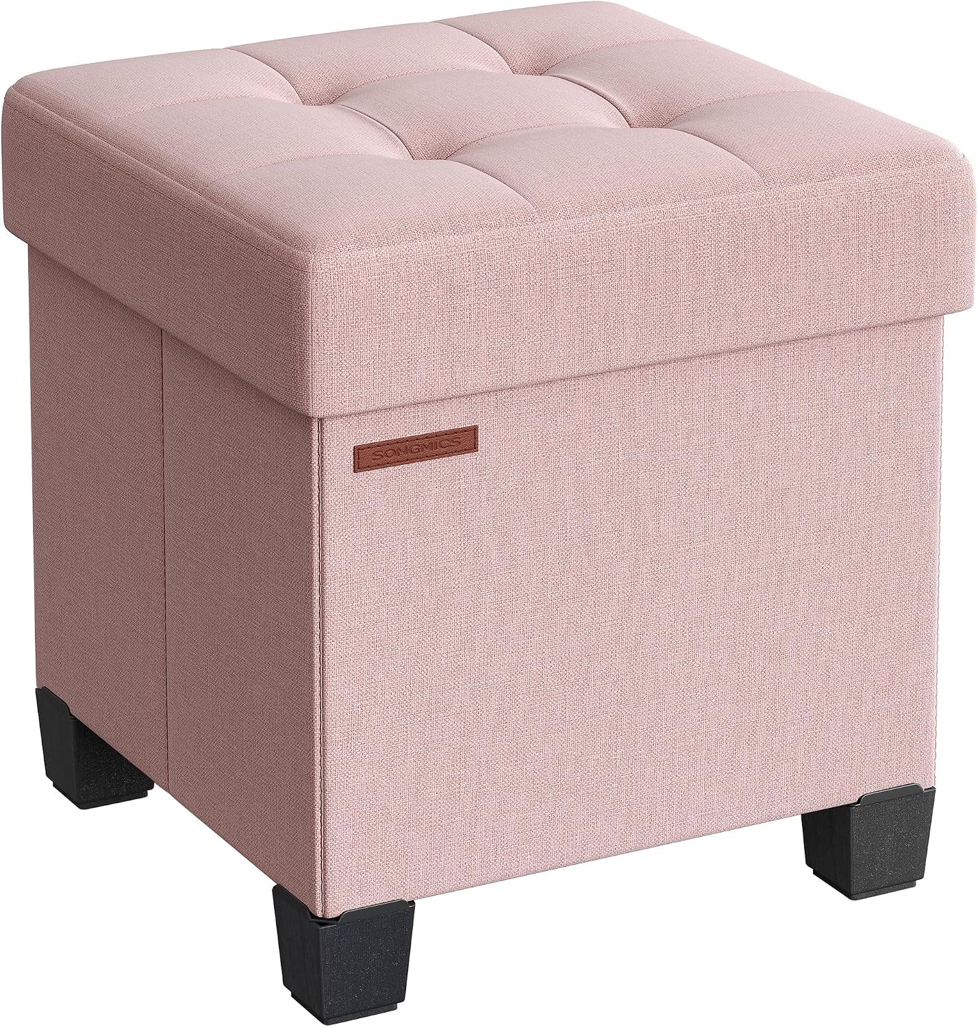 Angled view of a pink tufted square storage ottoman with black feet.