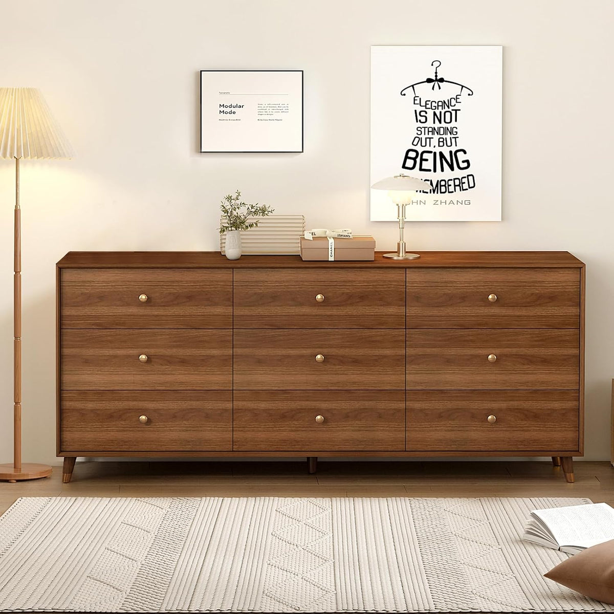 Wide brown dresser in a bedroom setting with lamp, framed art and decorative items on the tabletop