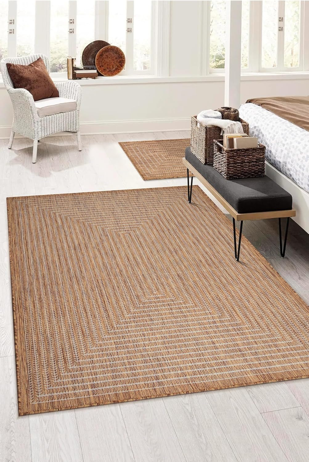 Bedroom scene with the natural beige rug under a bench and beside a bed on light wood floors and a small accent rug in back