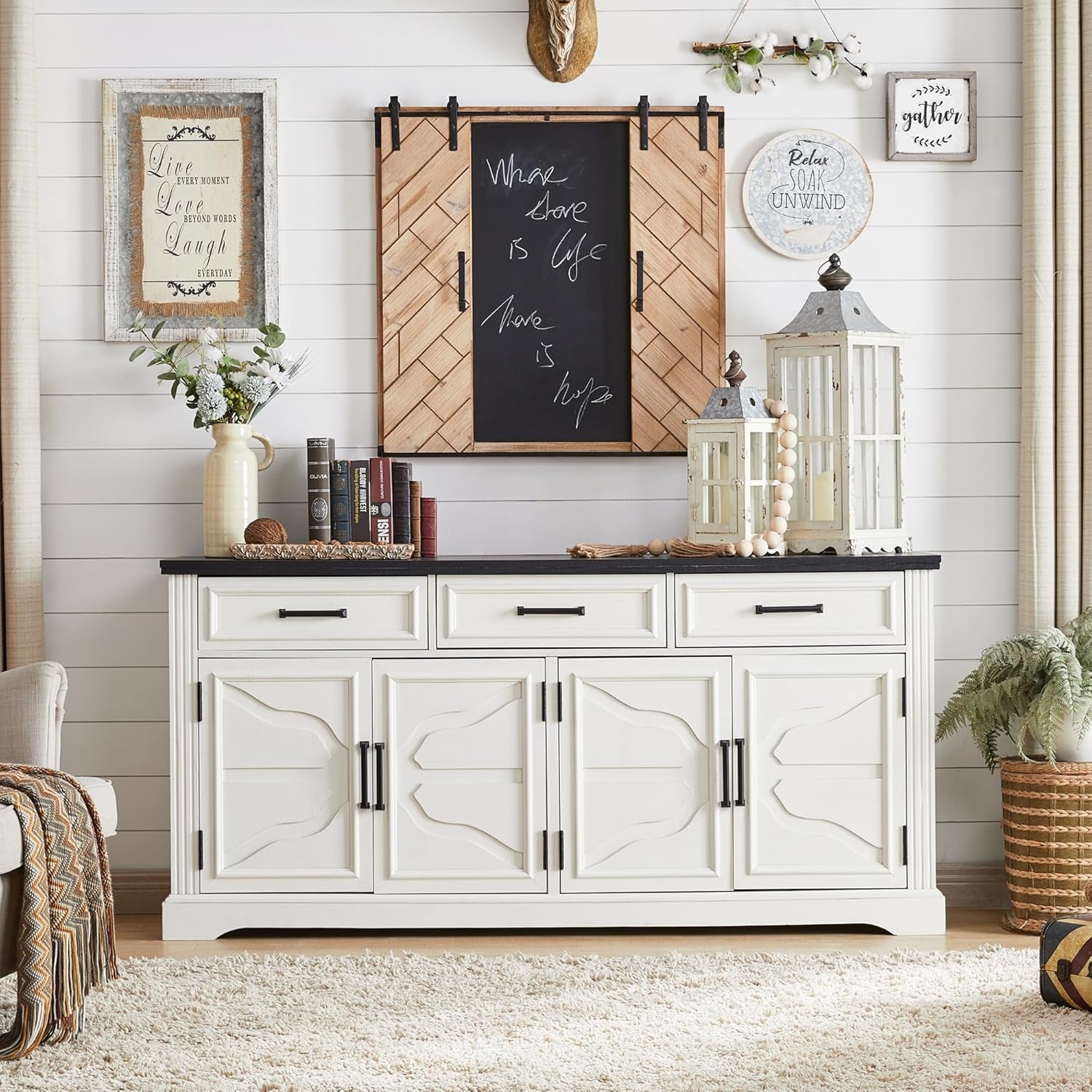 Straight-on scene of off-white buffet sideboard with decorative wall accents and tabletop lanterns
