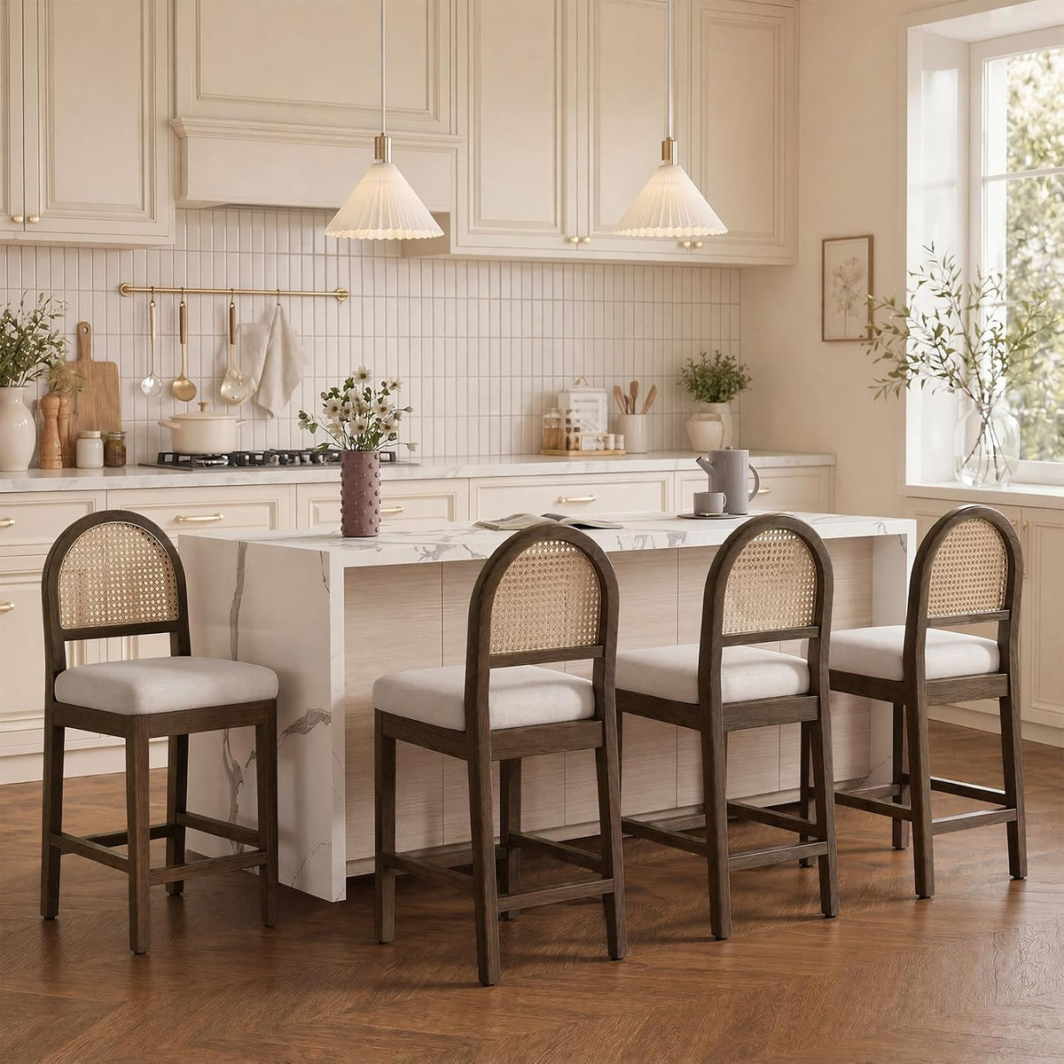 Four walnut-finish counter stools at an island showing arched rattan backs, cream chenille seats and wood footrests.