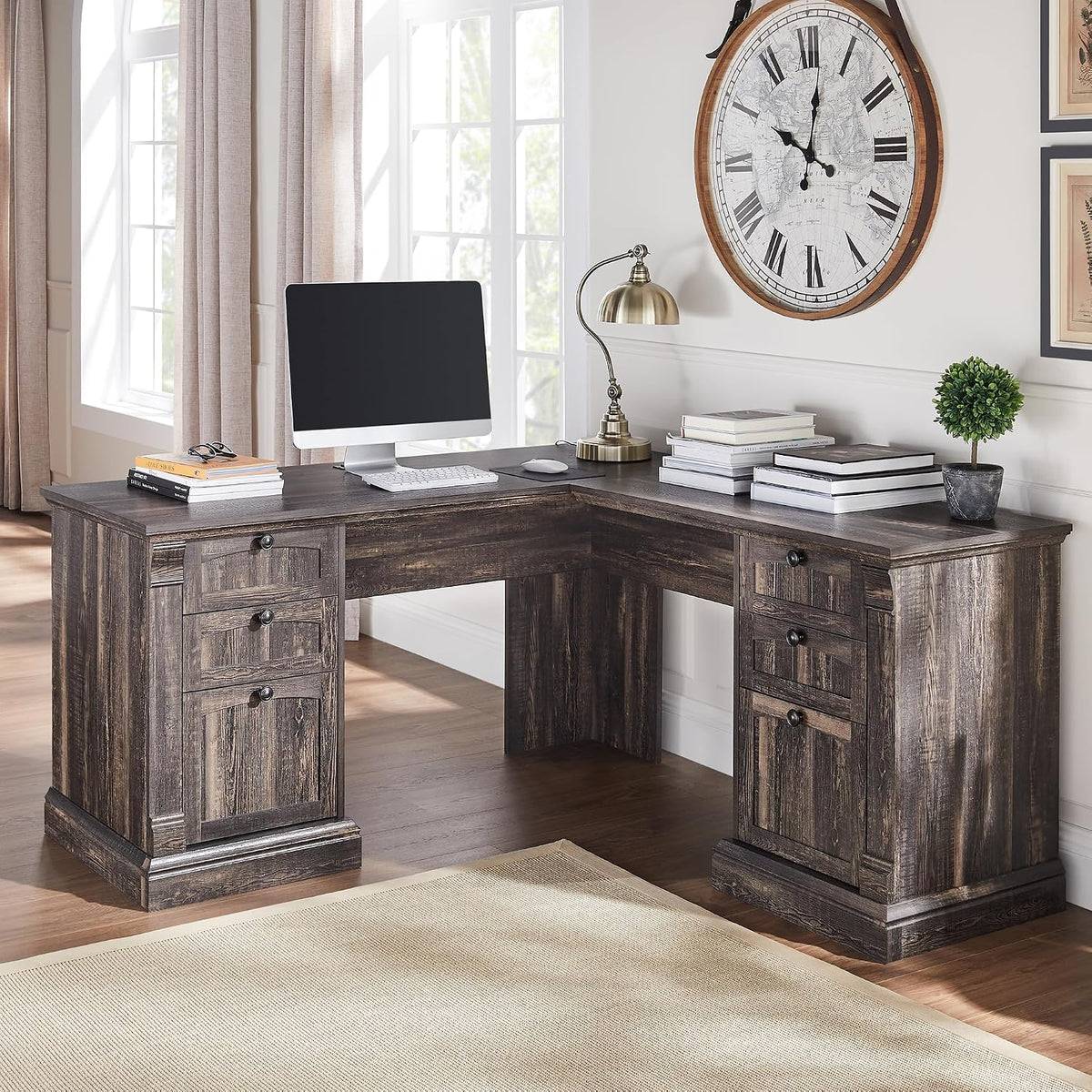 L-shaped executive desk in a dark distressed wood finish placed in a sunlit corner with monitor and lamp.