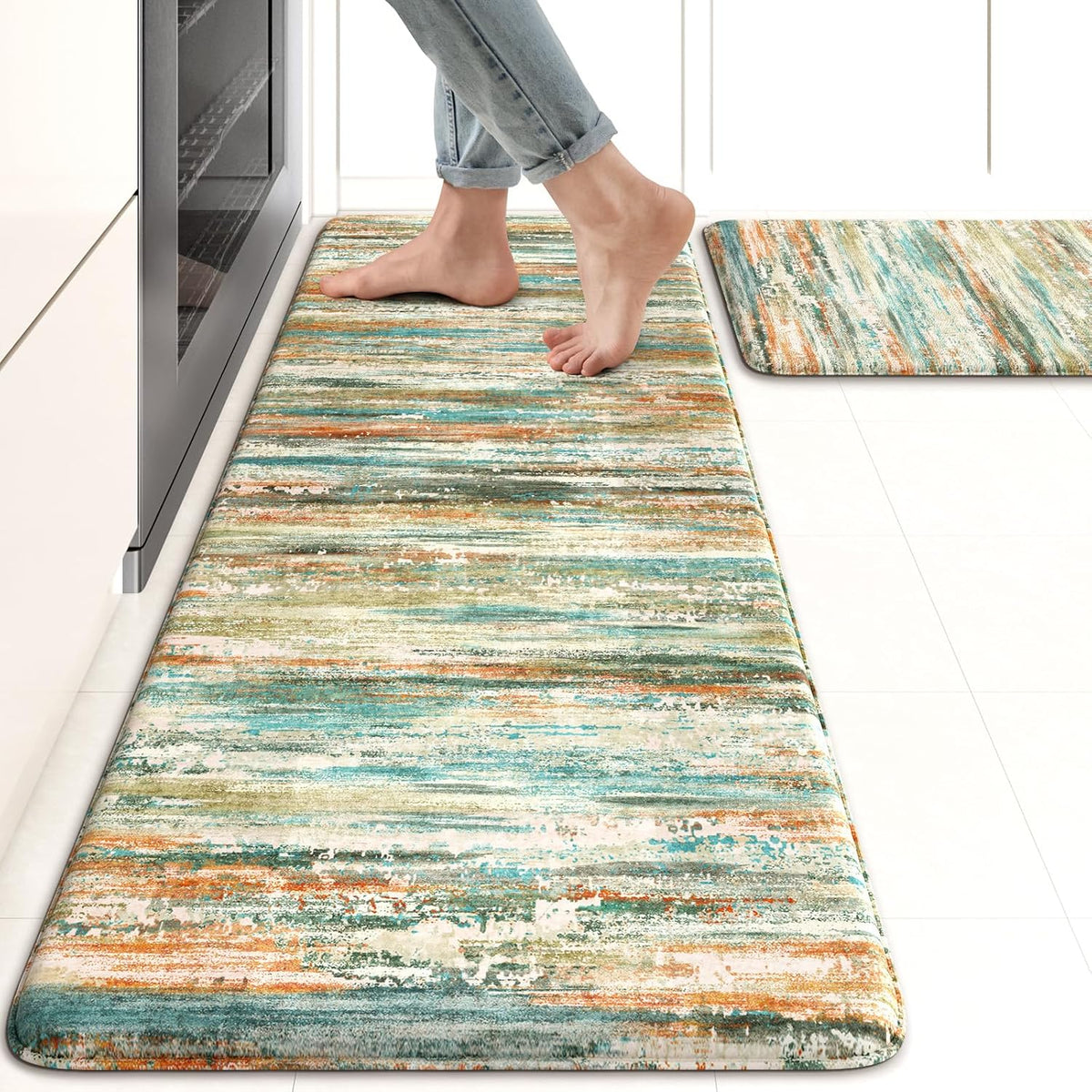 Long abstract striped kitchen mat in teal, orange and green tones with bare feet standing on it.