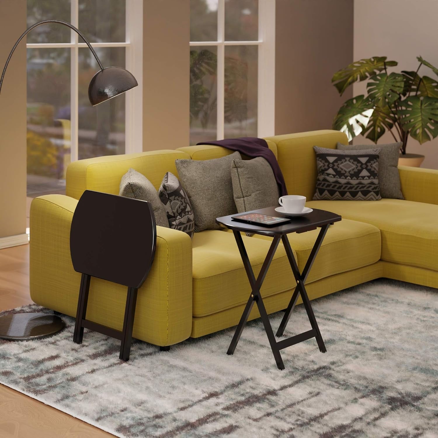 Single dark brown folding snack table next to a yellow sectional sofa with one table folded and one open