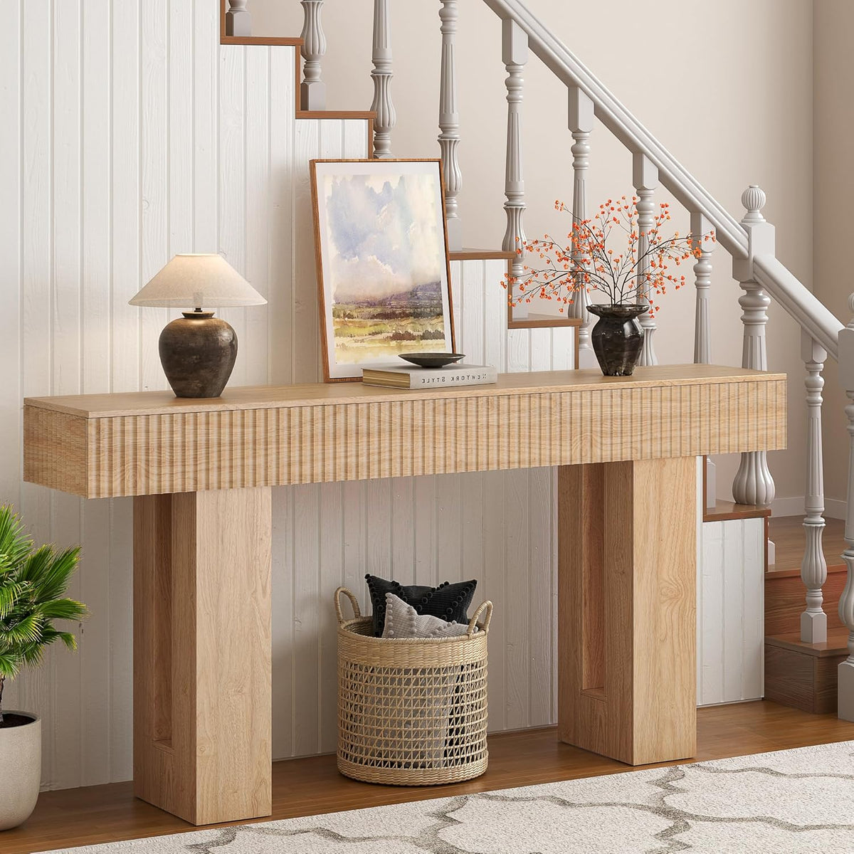Console placed beside a staircase with lamp, framed art, and a tall woven basket tucked beneath.