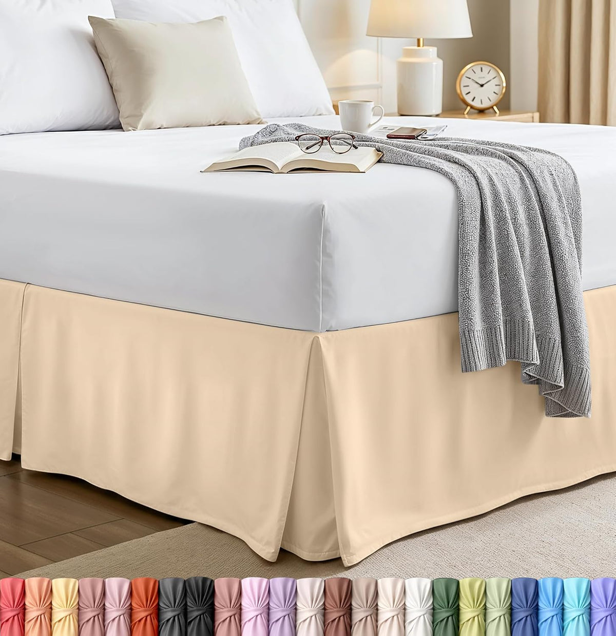 Styled bedroom corner showing a beige pleated bed skirt beneath a white mattress and gray throw.