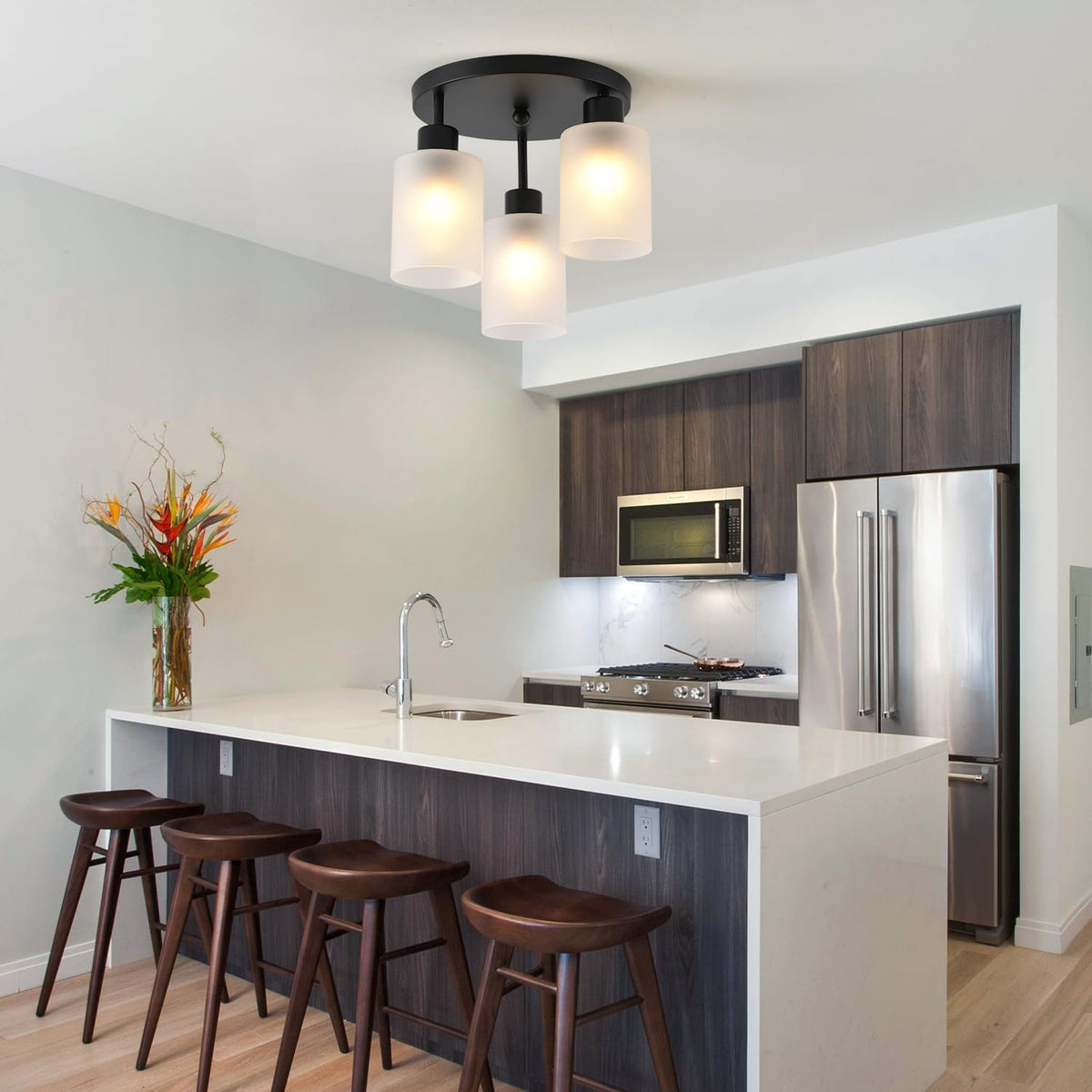 Fixture installed above a modern kitchen island with dark wood cabinets and three bar stools.