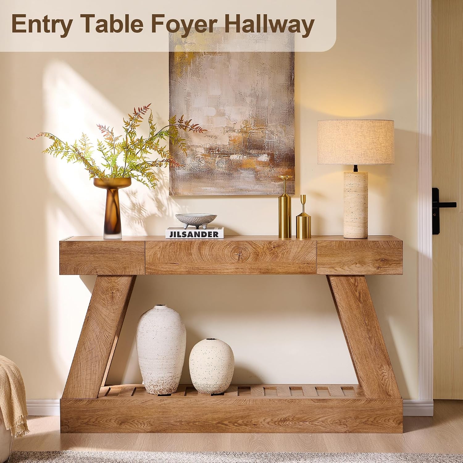 Front room view of the light brown console table styled with vases, a lamp, and wall art.