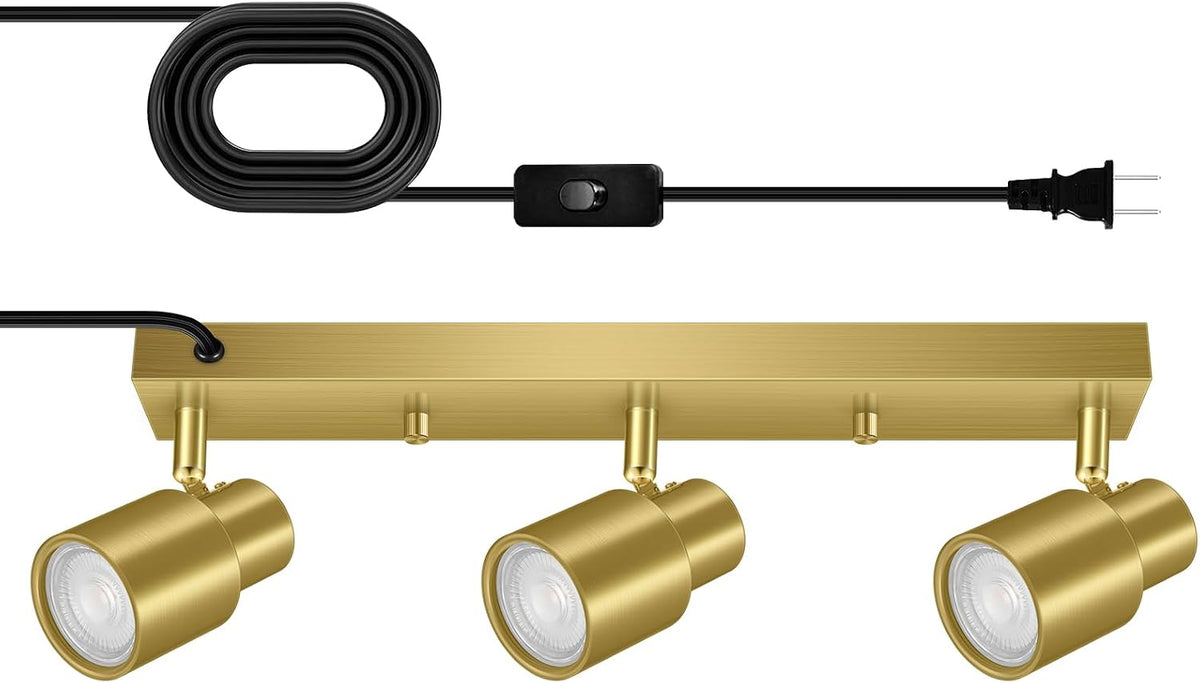 Brushed gold track bar with three adjustable gold spotlight heads and black coiled cord with inline switch