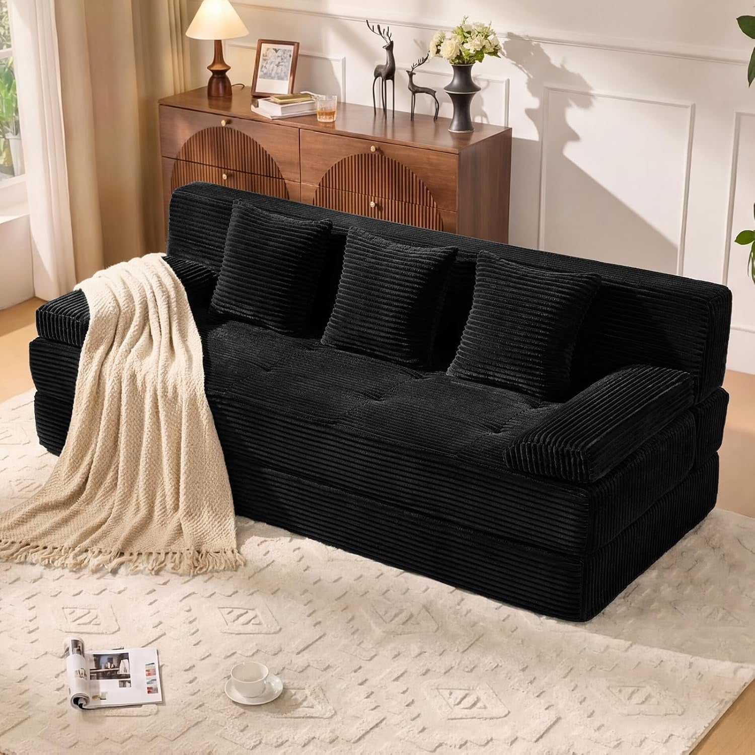 Three-seat ribbed corduroy sofa staged in a living room with throw blanket and four square pillows