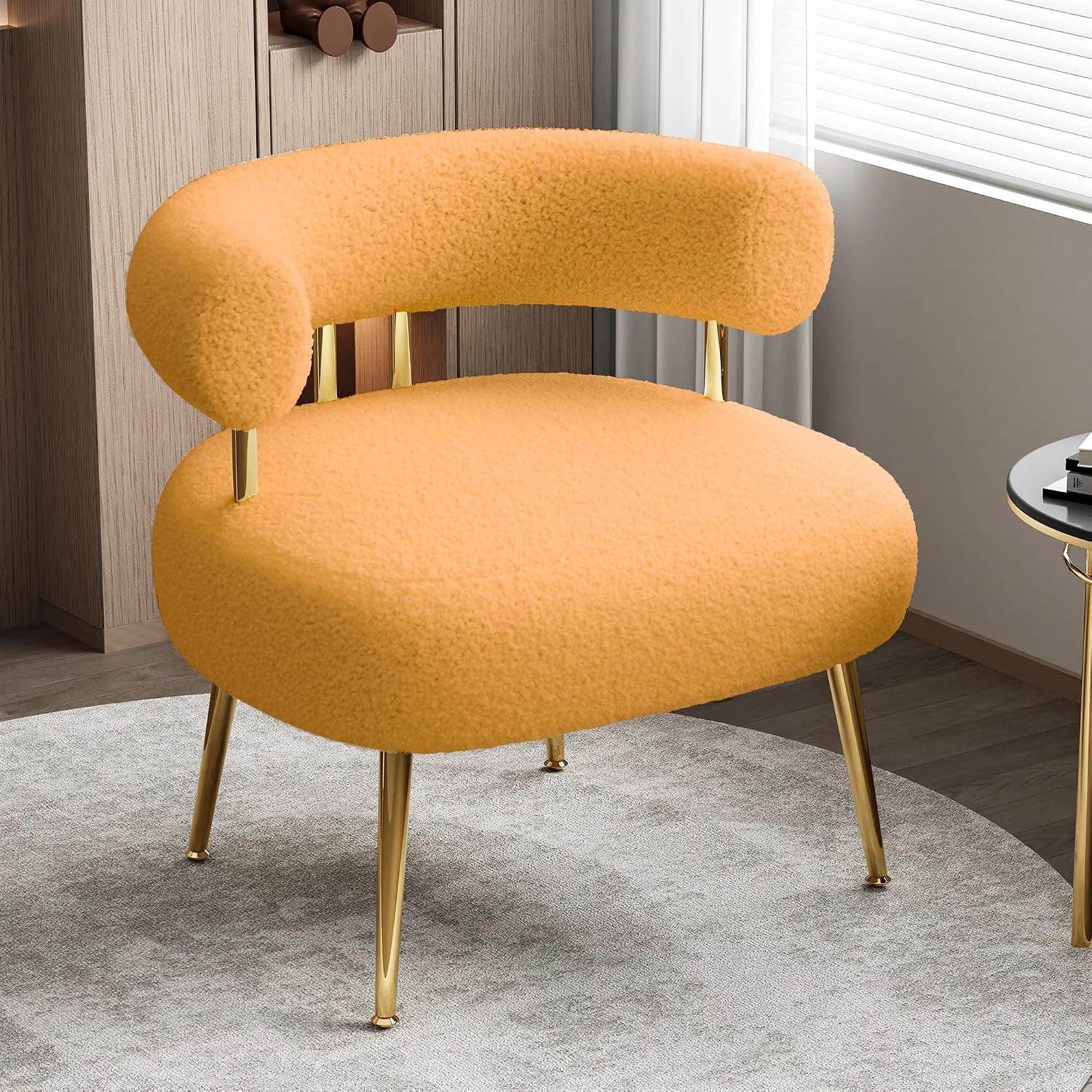 Plush rounded barrel chair in warm orange sherpa with gold metal legs on a gray rug.
