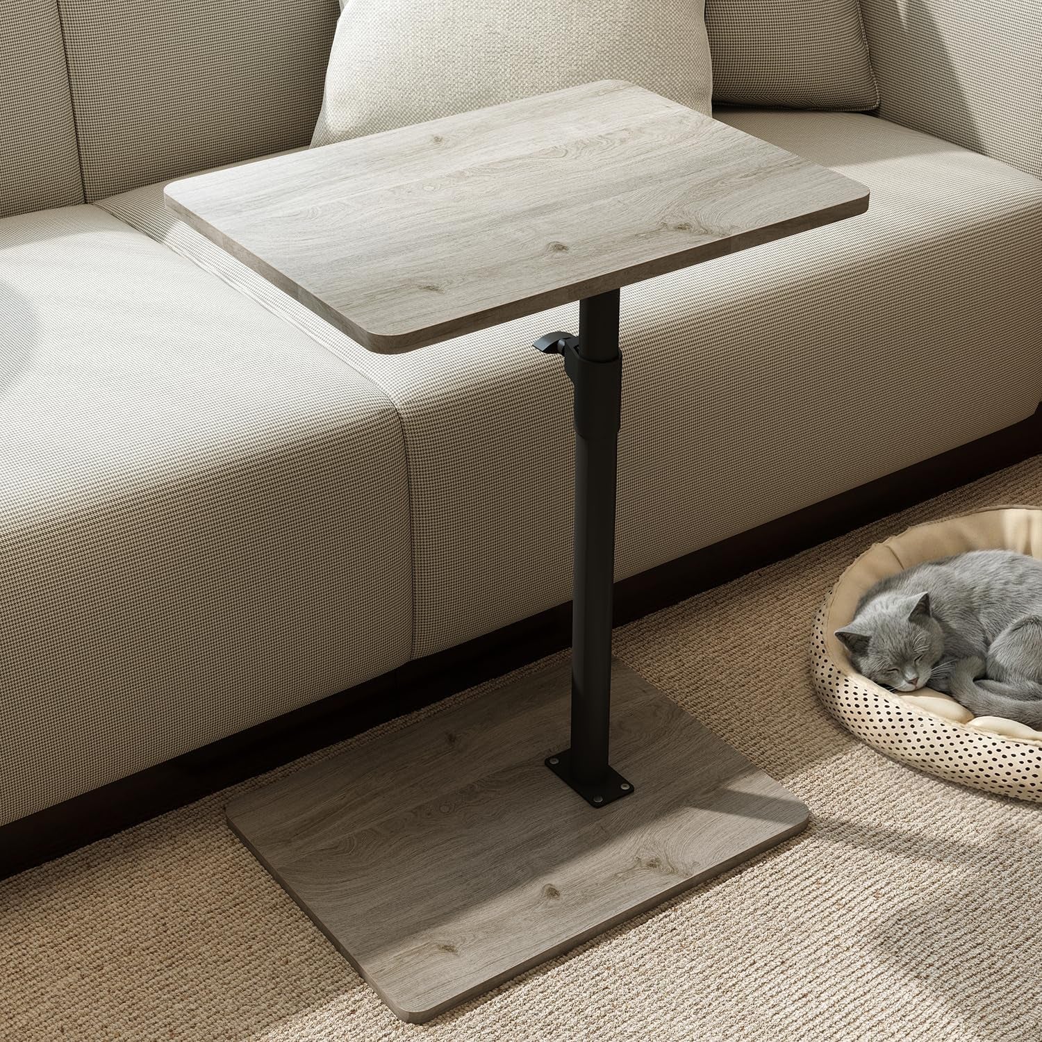 Light gray wood C-shaped side table beside beige sofa and a sleeping gray cat in a round bed.