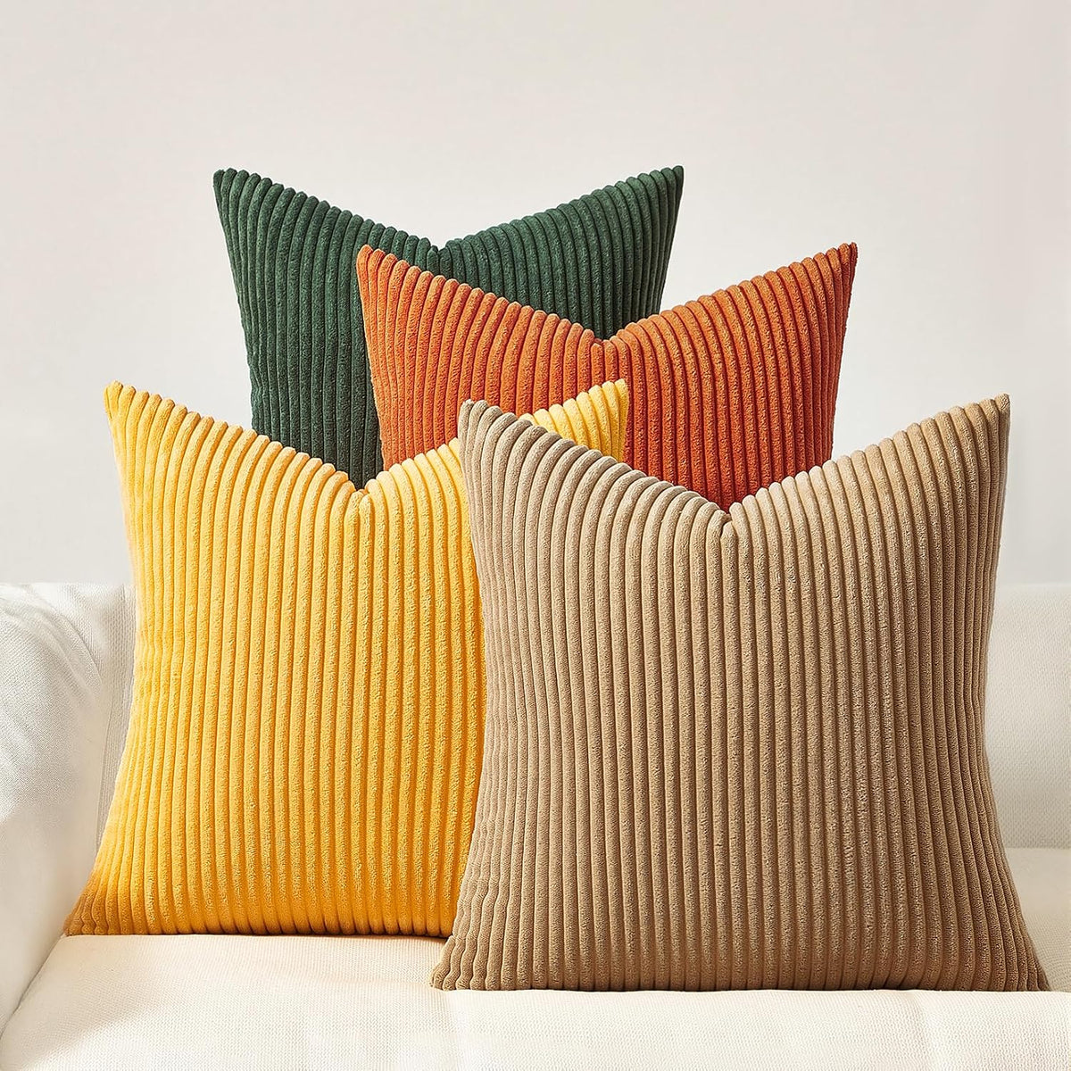 Close grouping of four ribbed corduroy pillows in soft pink tones on a pale couch.