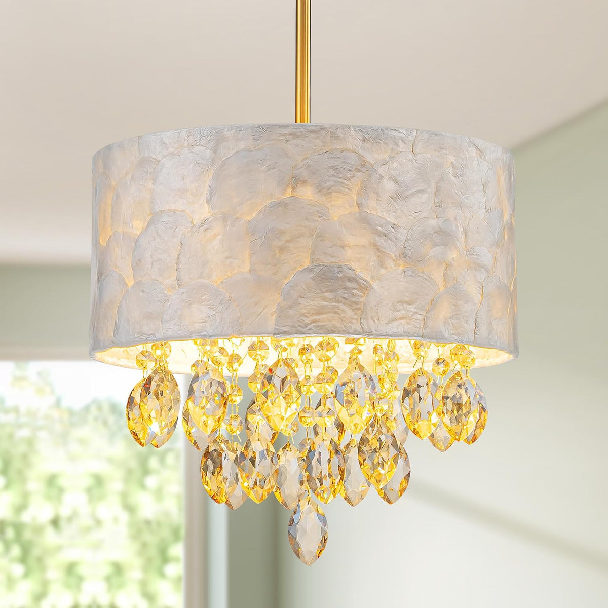 Close-up of the lit drum shade and faceted crystal drops hanging from a gold-finished rod.