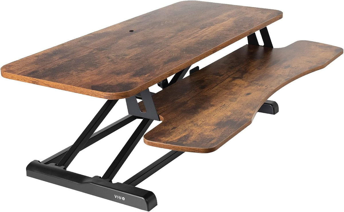 Angled perspective showing top and curved keyboard shelf with black X-frame and wood grain finish