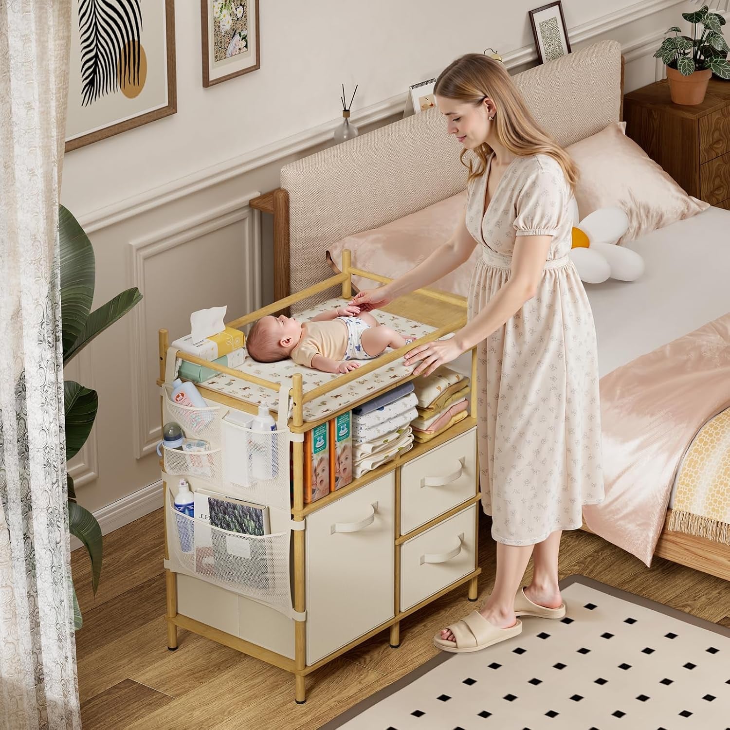 Woman changing a baby on a bamboo changing table with three drawers, open shelves and mesh pockets beside a bed.