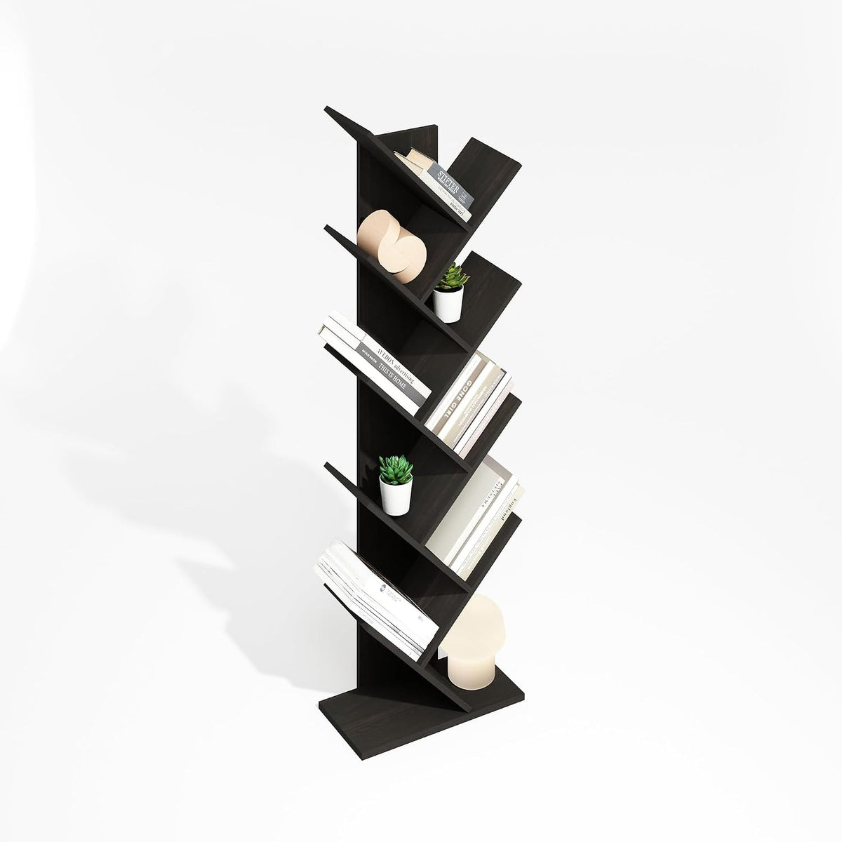 Angled studio view of a tall zigzag bookcase holding books, small potted plants and a lamp on white background