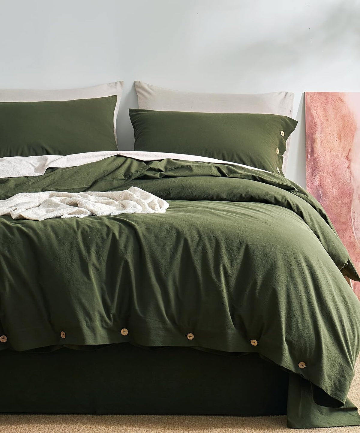 Bed styled with deep olive-green duvet and matching pillowcases, wooden buttons along the hem.