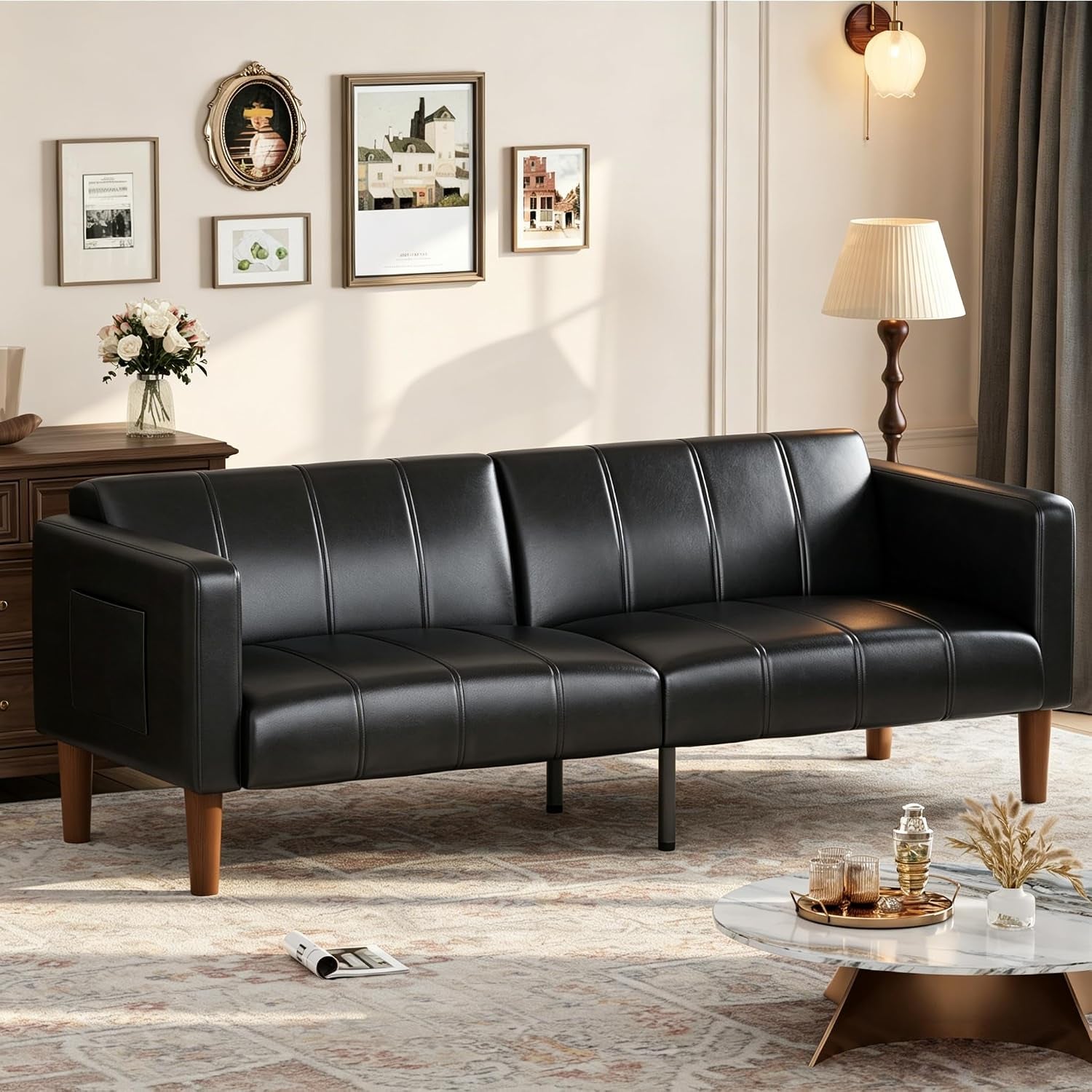 Three‑seat black faux‑leather futon sofa styled in a living room setting