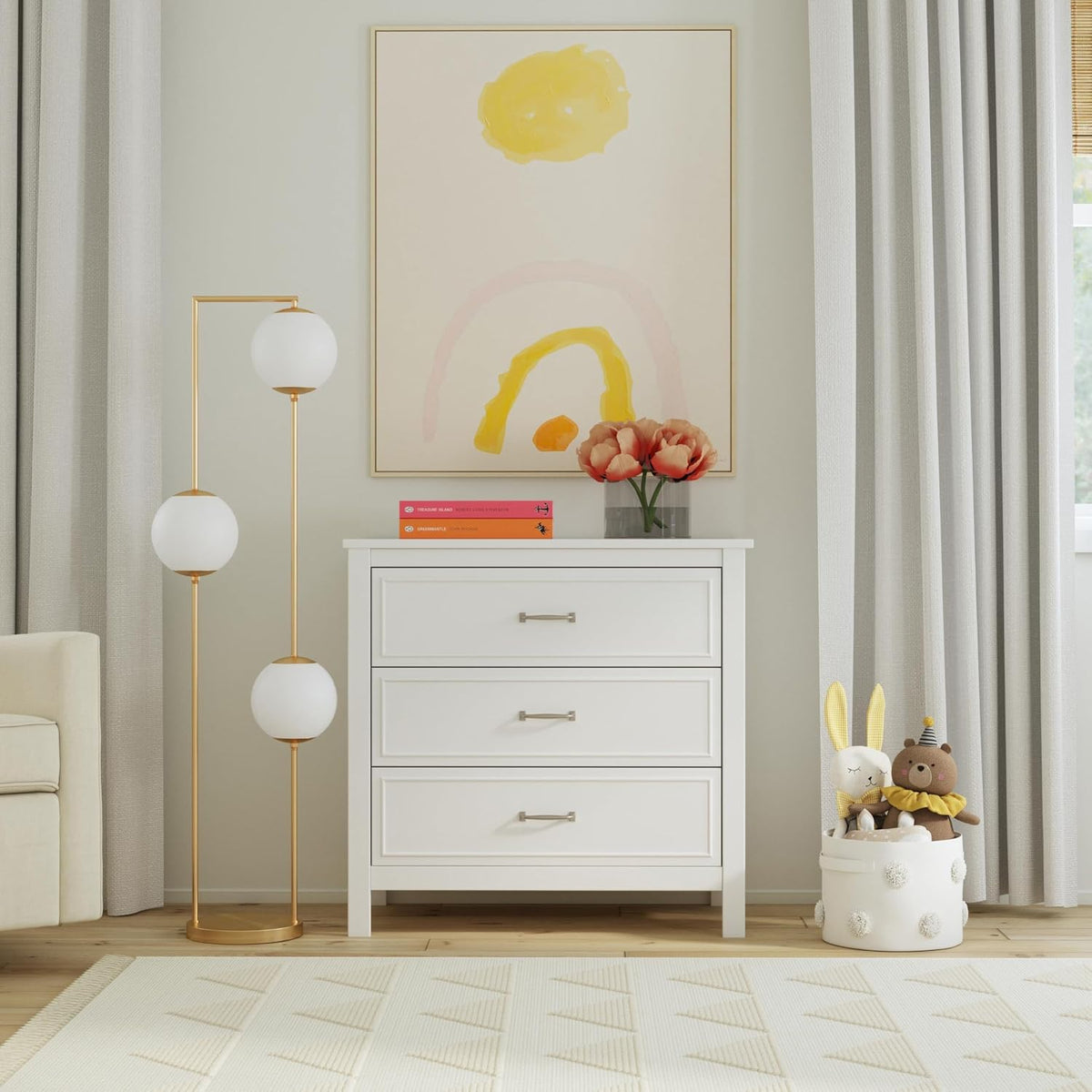 Styled scene showing the dresser top with a lamp and framed artwork in a light nursery interior