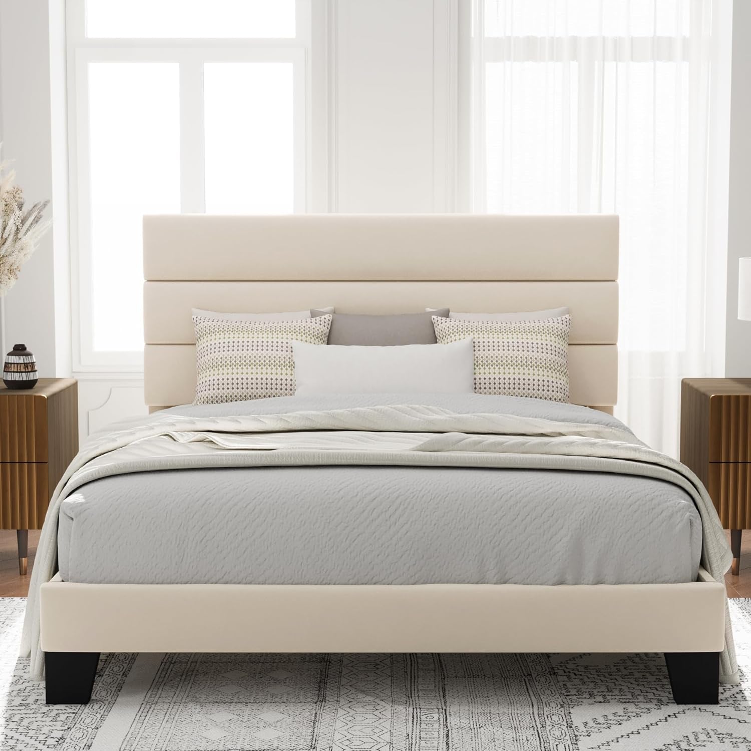 Front room view of a cream bed frame with a tall three-panel headboard and pale bedding.