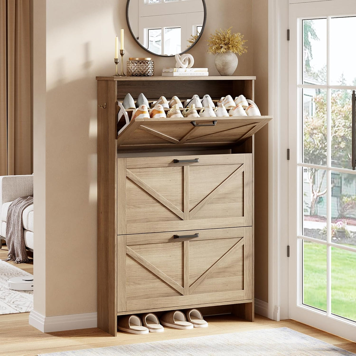 Three-quarter view of a tall light-wood shoe cabinet with the top tilt drawer open showing shoes and slippers tucked under.