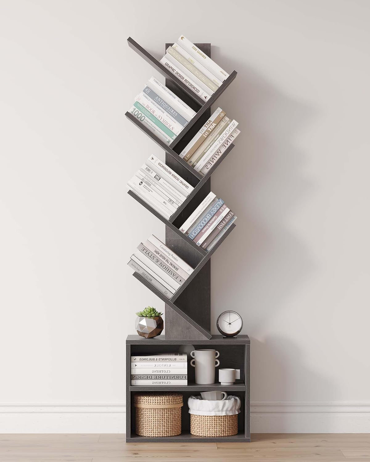 Tall six-tier tree bookshelf in dark gray with books and two lower cubbies against a light wall.