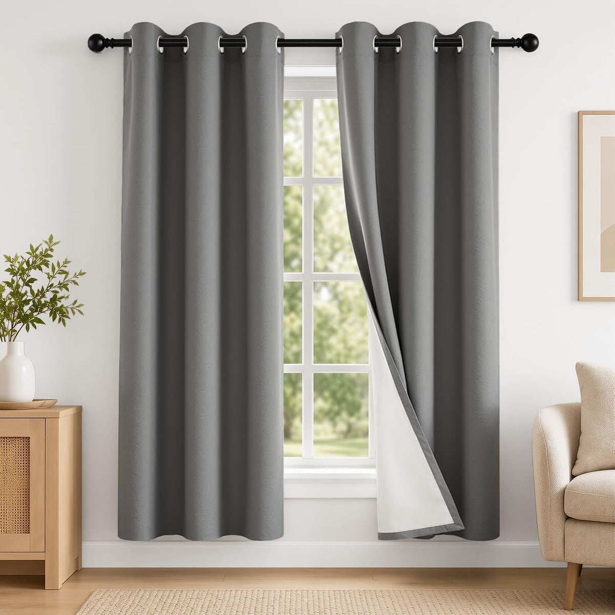 Dark gray grommet curtains hung on a rod framing a window, one panel pulled back to show white backing
