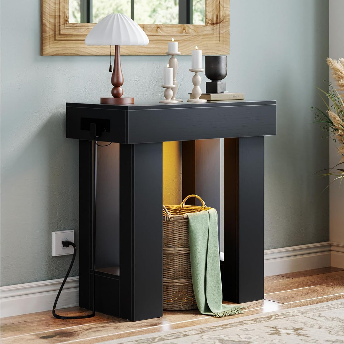 Matte black console table three-quarter view showing lit interior, tabletop decor and visible power cord to wall