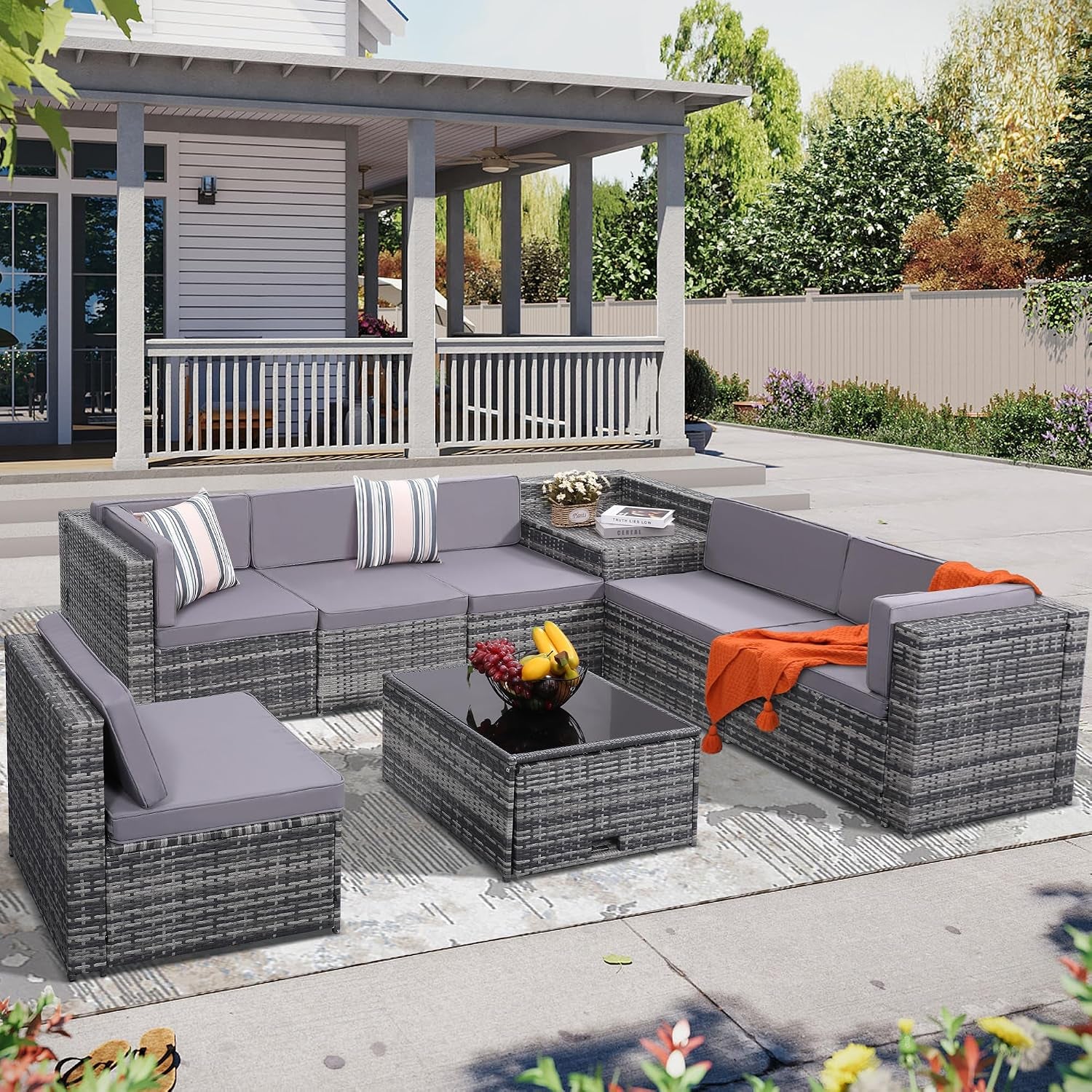 L-shaped gray wicker modular sectional with gray cushions, center coffee table and orange throw on a patio.