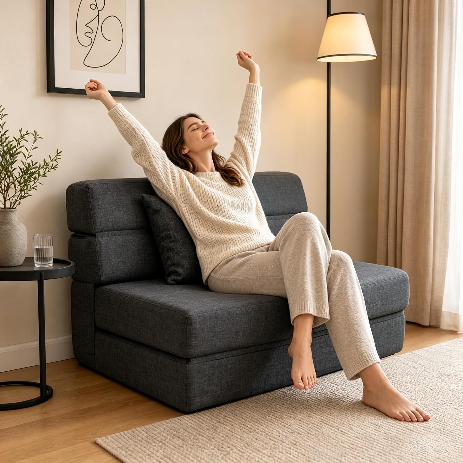 Person relaxing on the dark grey futon sofa bed in sofa position in a bright living room setting