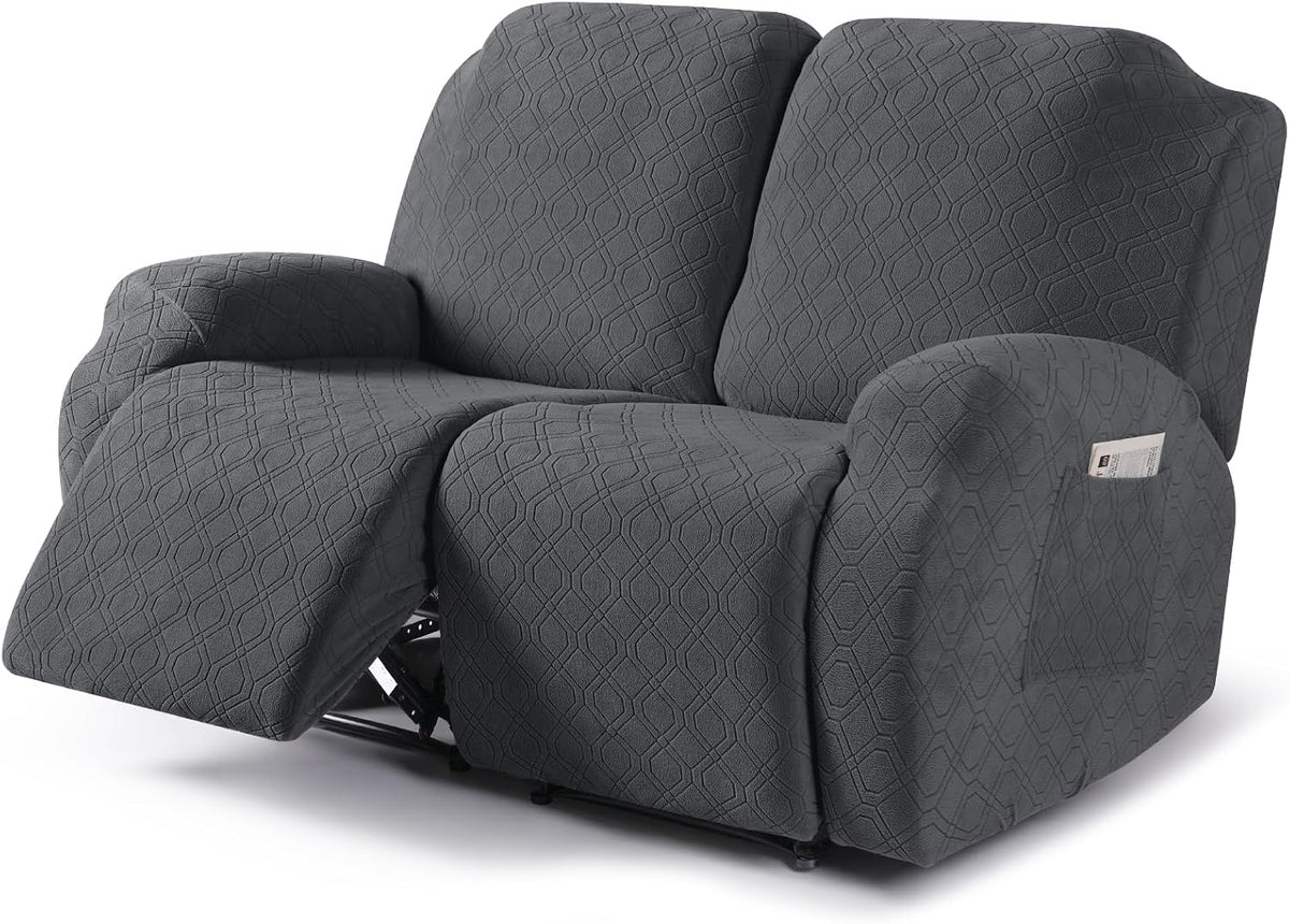 Angled front view of a dark gray textured recliner cover on a reclining loveseat with one footrest extended and arm pocket.