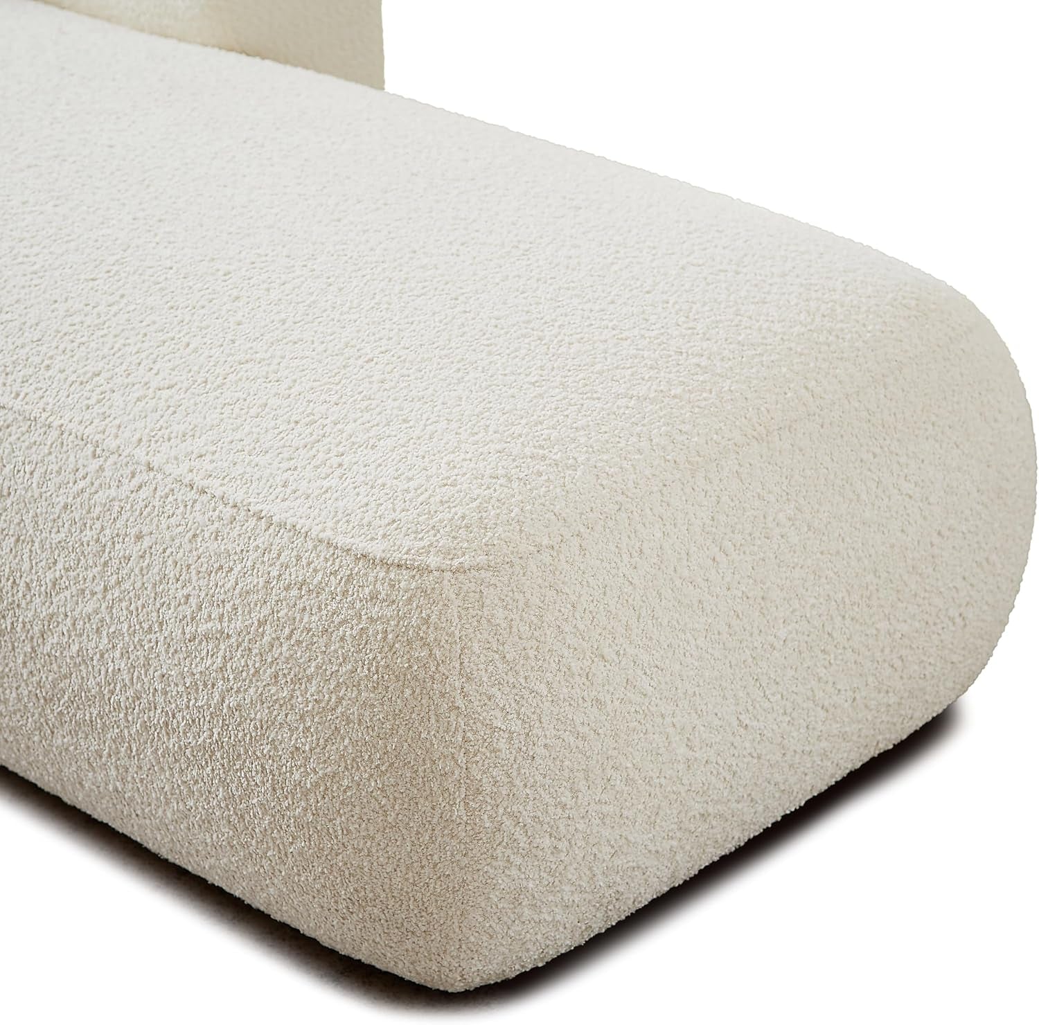 Close-up of cream boucle fabric texture and rounded corner of the chaise seat