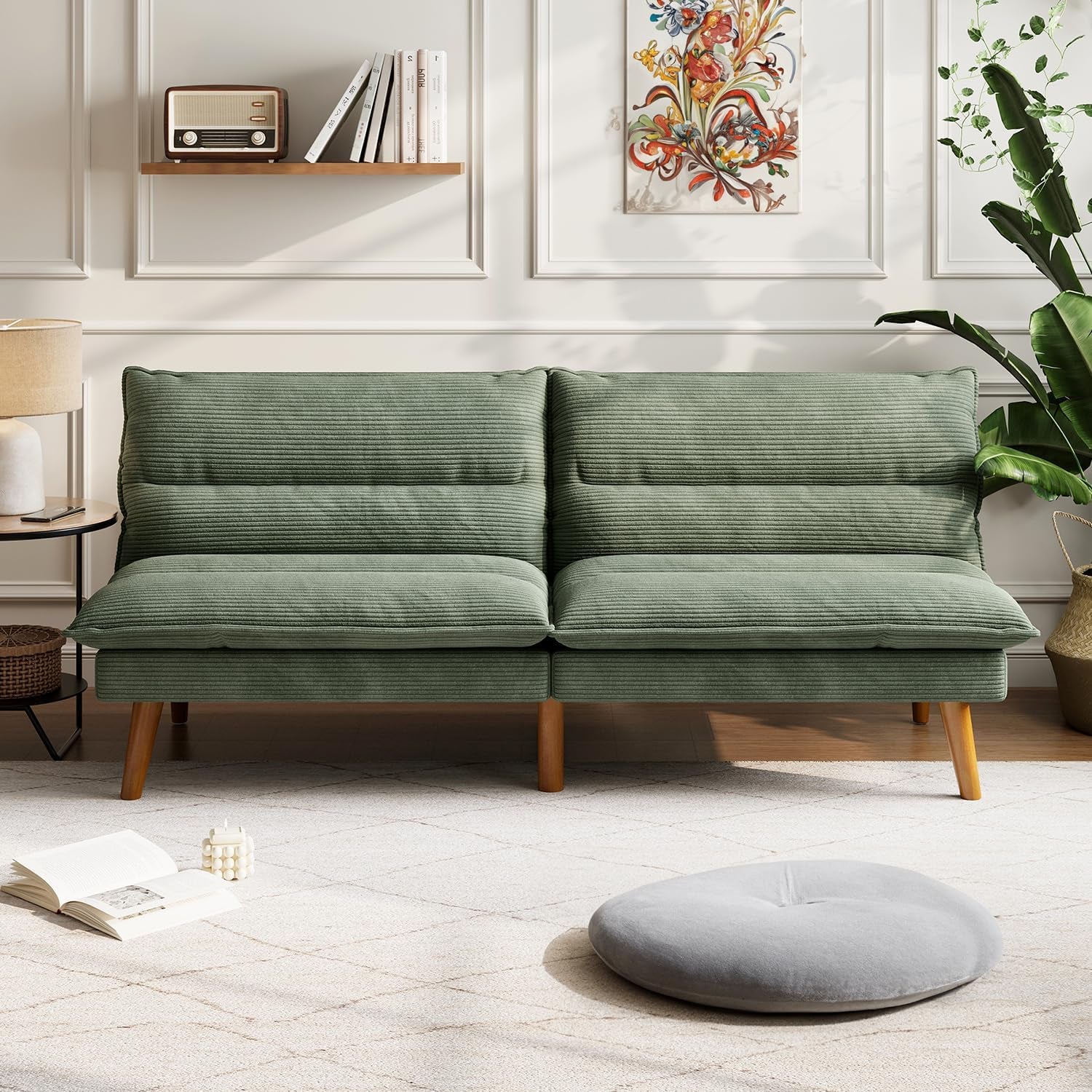Front-facing view of a green corduroy convertible loveseat with wooden legs against a paneled wall.