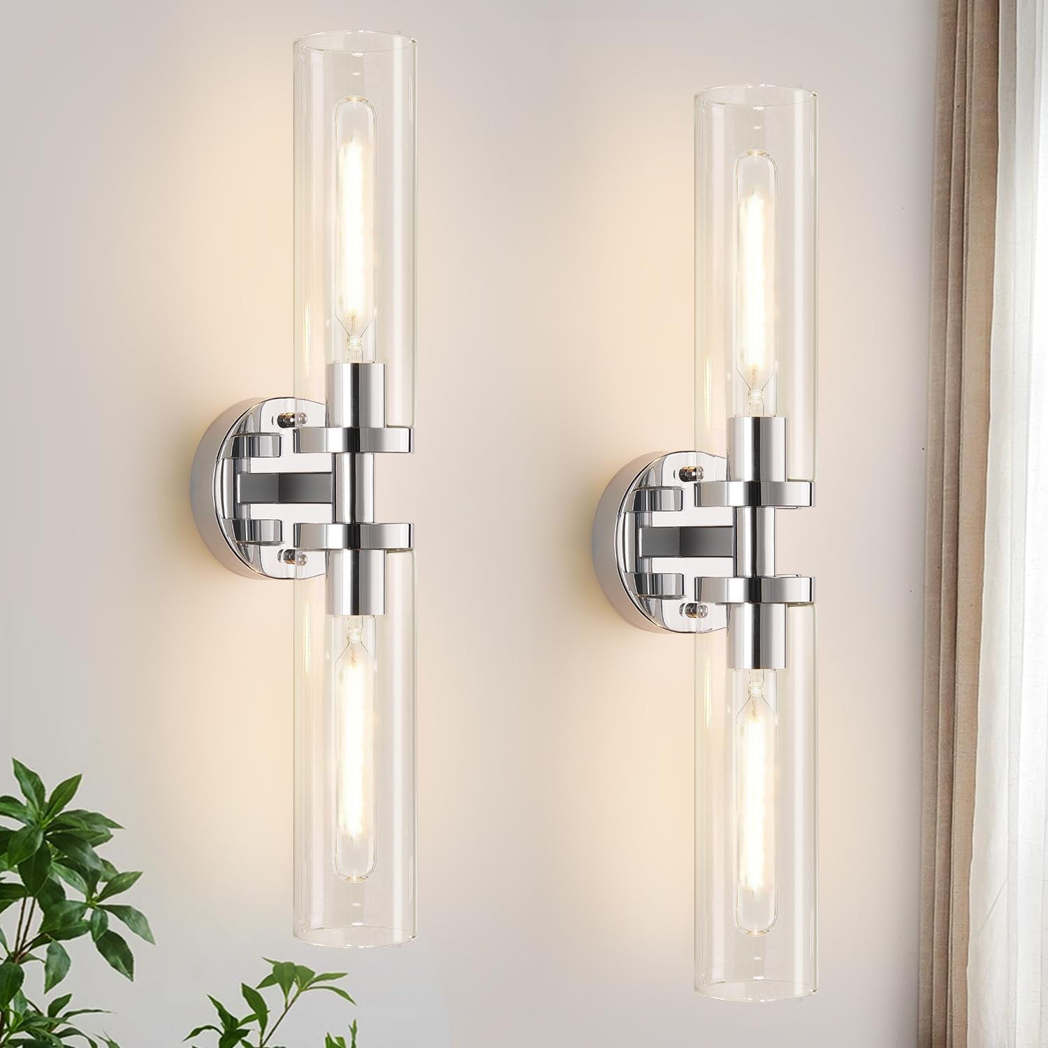 Two vertical chrome wall sconces with clear cylindrical glass shades shown side by side.