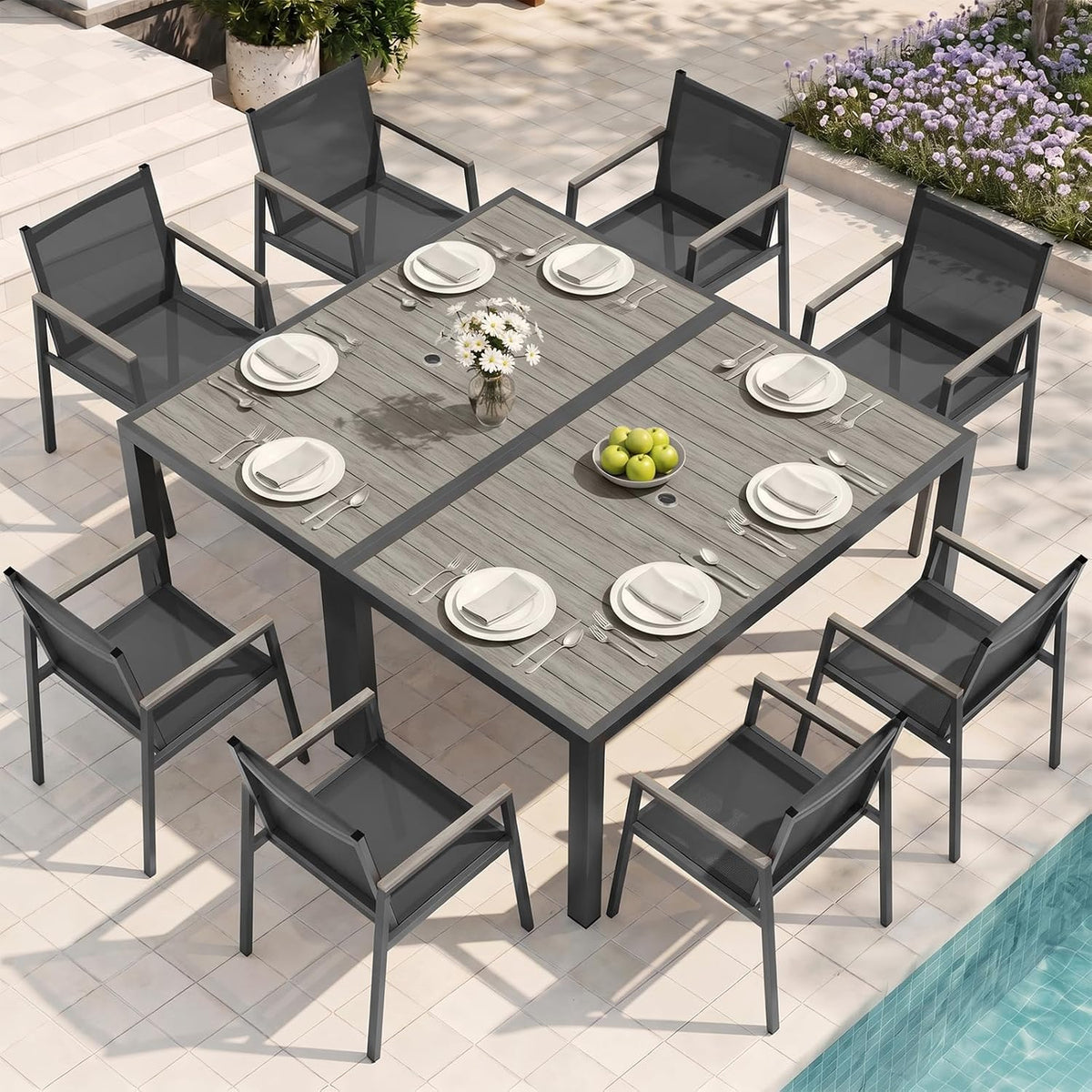 Joined dark-top tables staged poolside with place settings and eight gray-framed chairs.