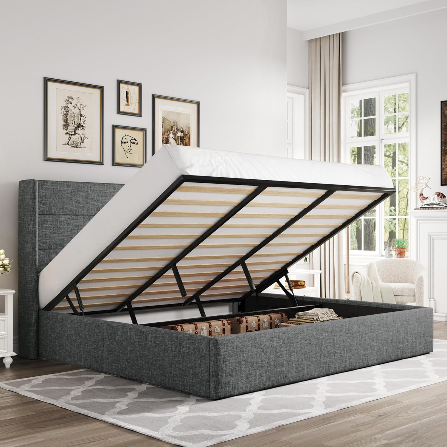 Raised mattress on a dark gray upholstered storage bed exposing the open storage area beneath.