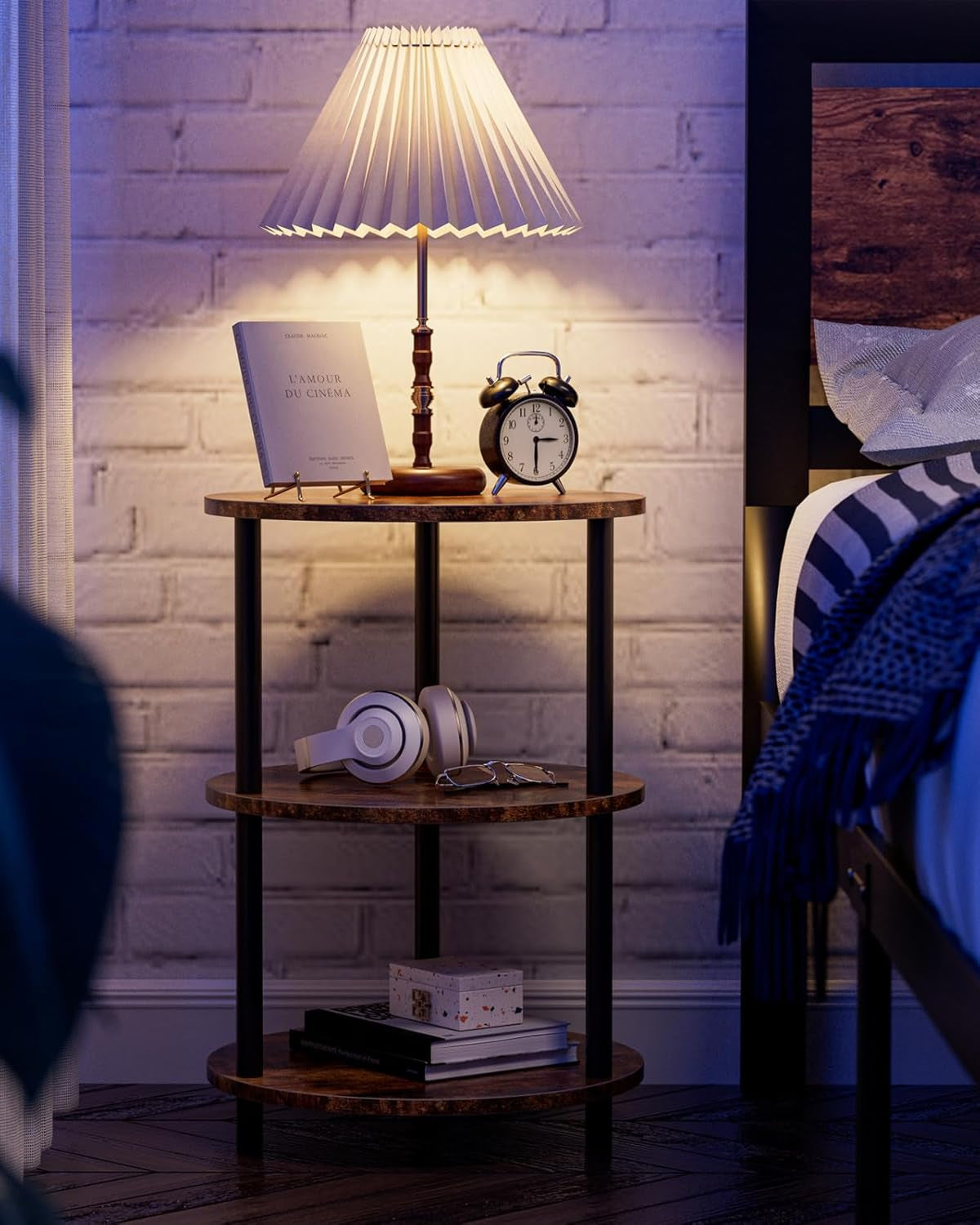 Single round three-tier side table used as bedside table with lamp and alarm clock in a bedroom scene