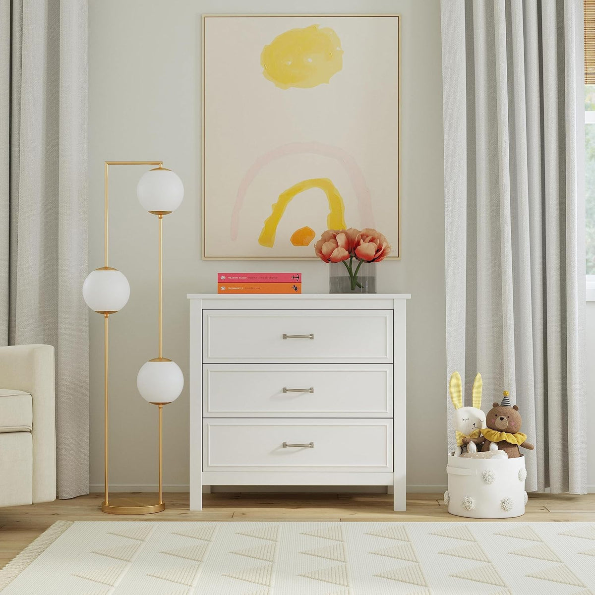 Front-facing dresser styled in a nursery with framed art above and a toy basket beside it