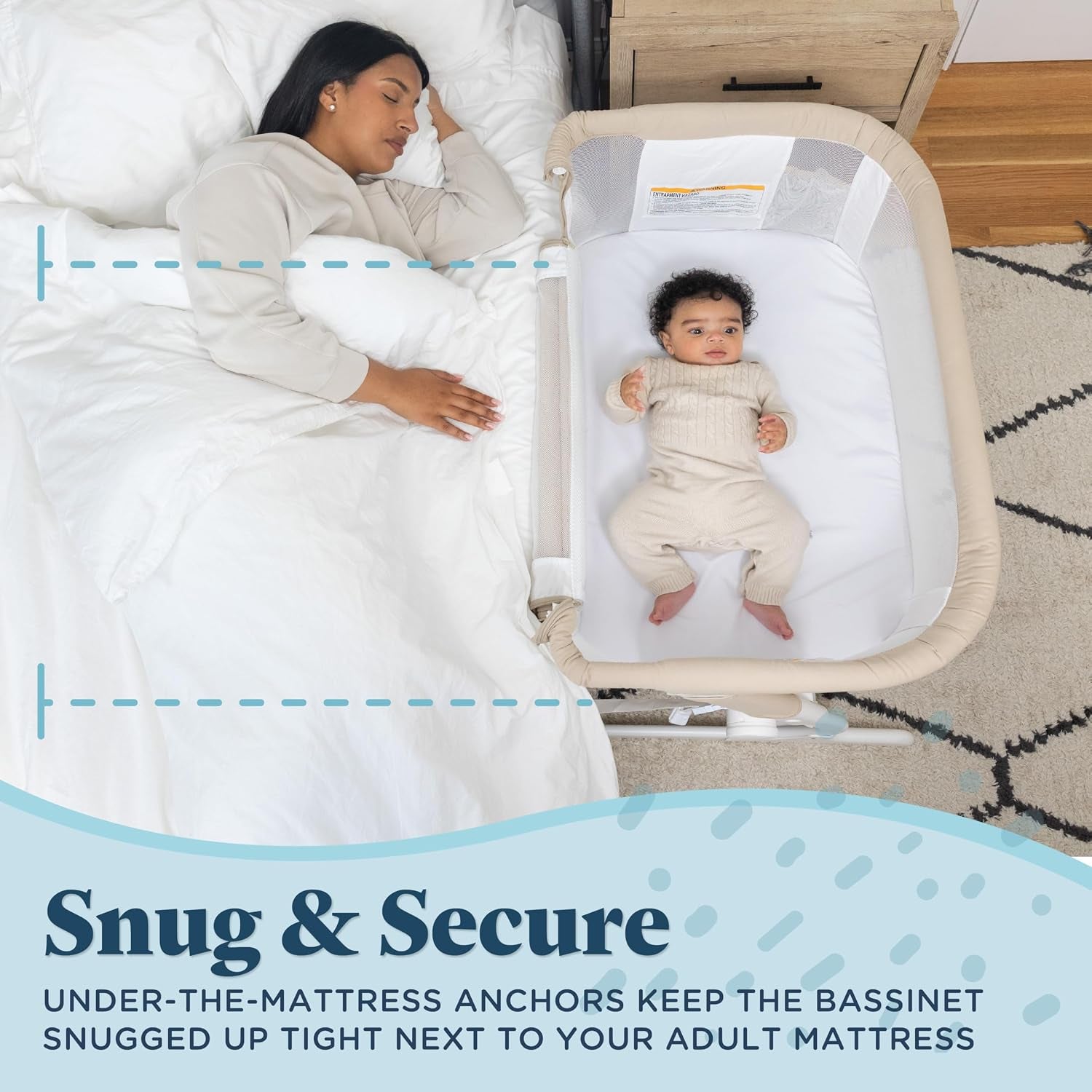 Overhead view of a woman asleep in bed next to a beige bassinet with a baby inside on a white sheet.