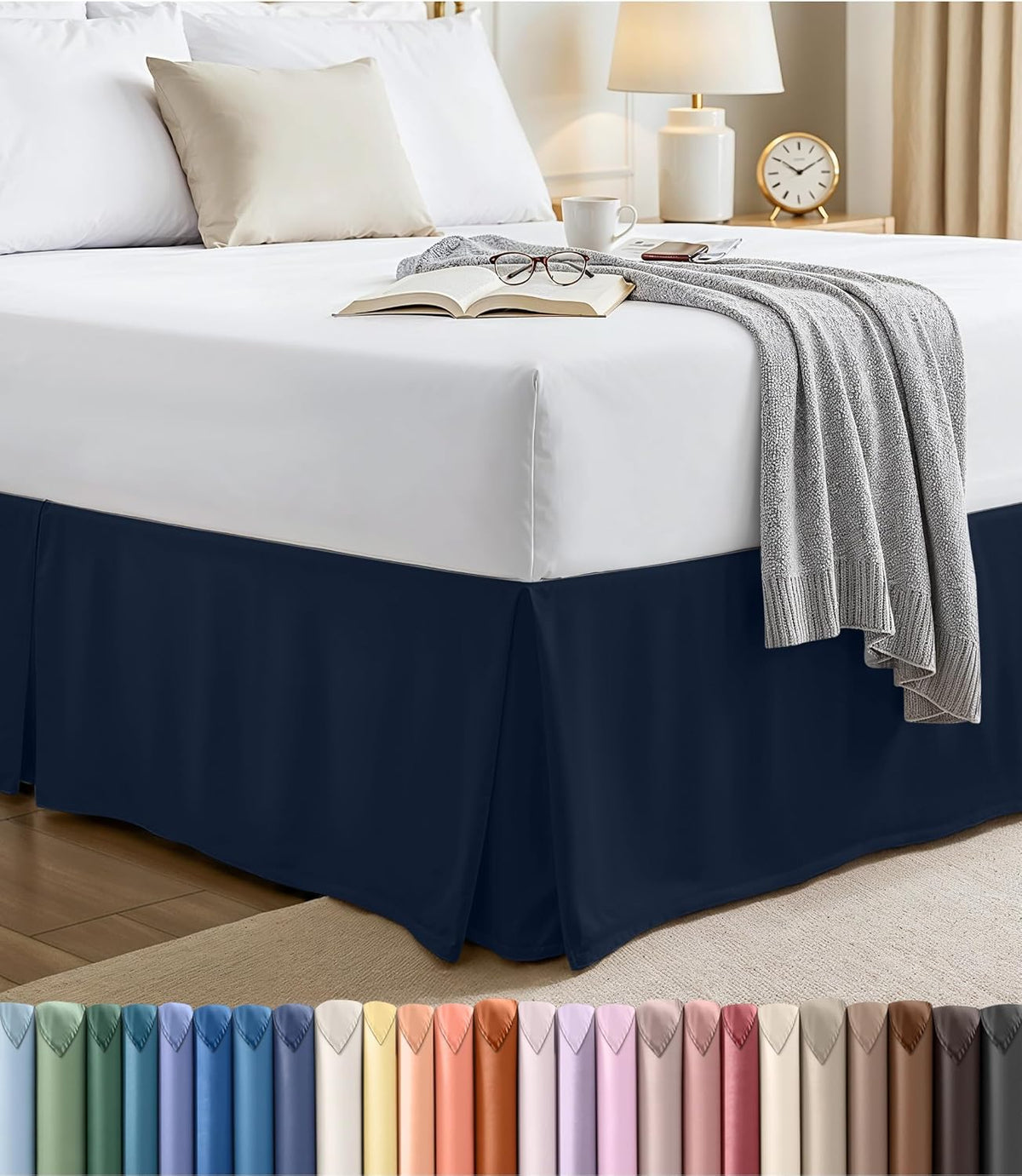 Bed with a dark navy pleated bed skirt and a white fitted sheet, corner pleat visible.