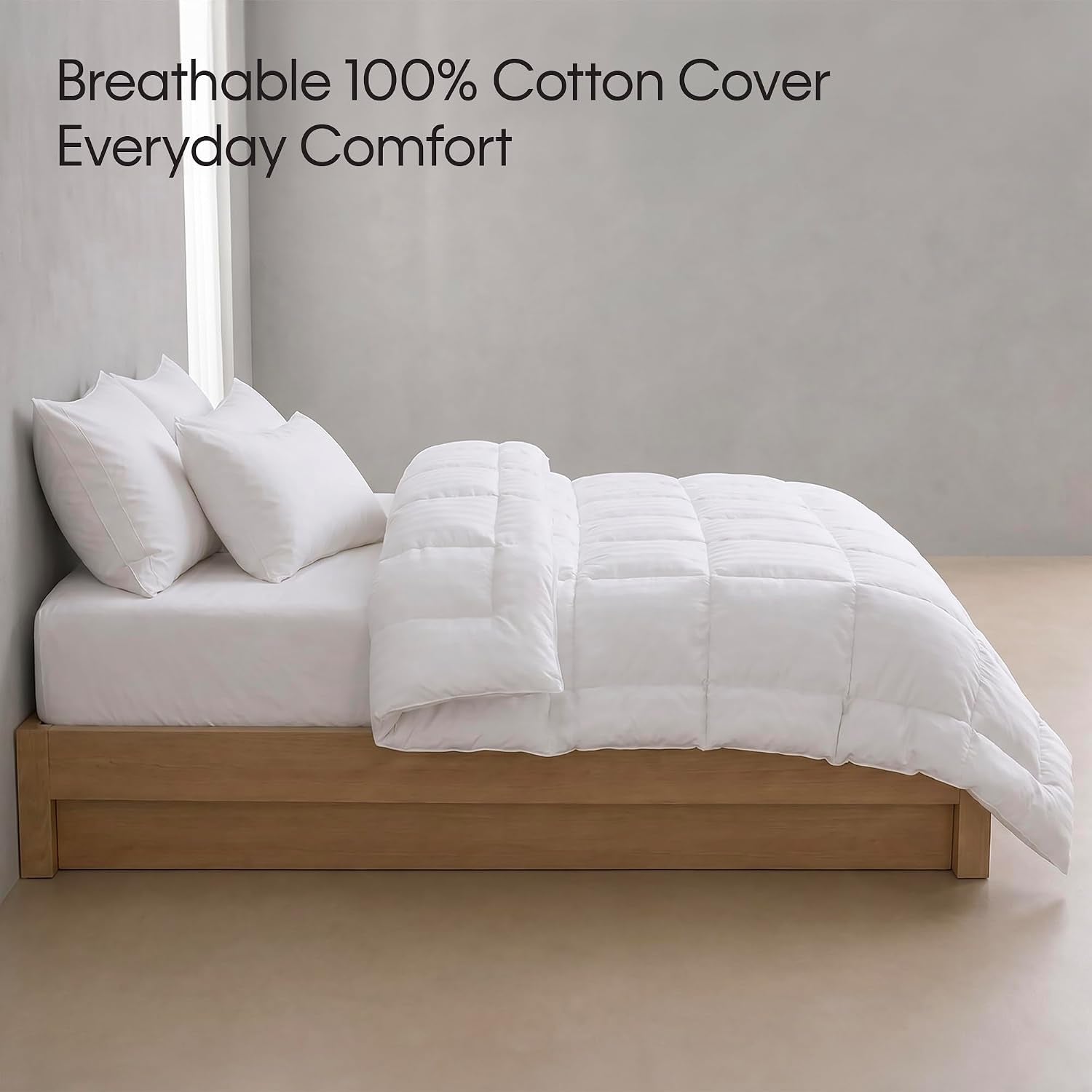 Side profile of a bed with a white striped comforter folded back showing quilted box stitching
