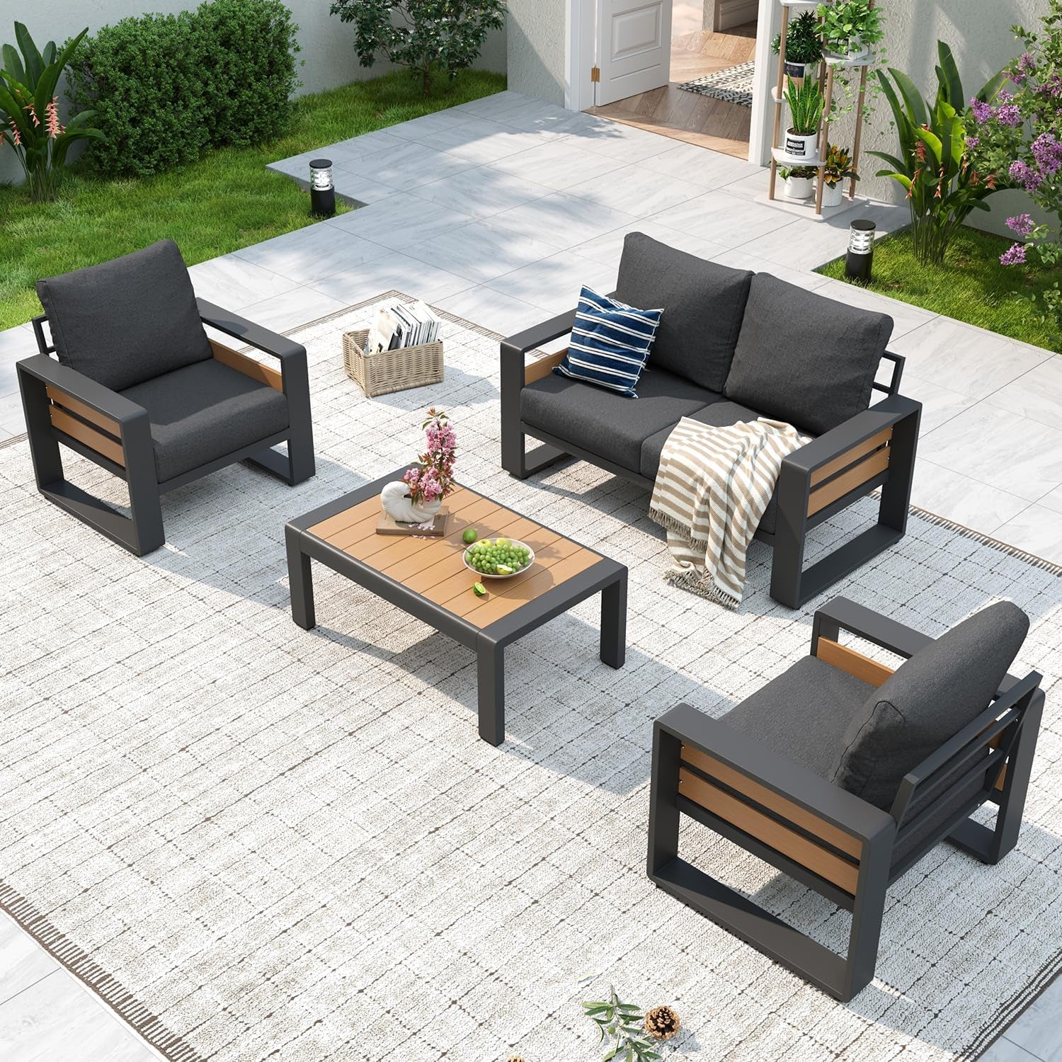 Outdoor sofa set with dark frame and charcoal cushions paired with a low wooden-top coffee table on a light rug.